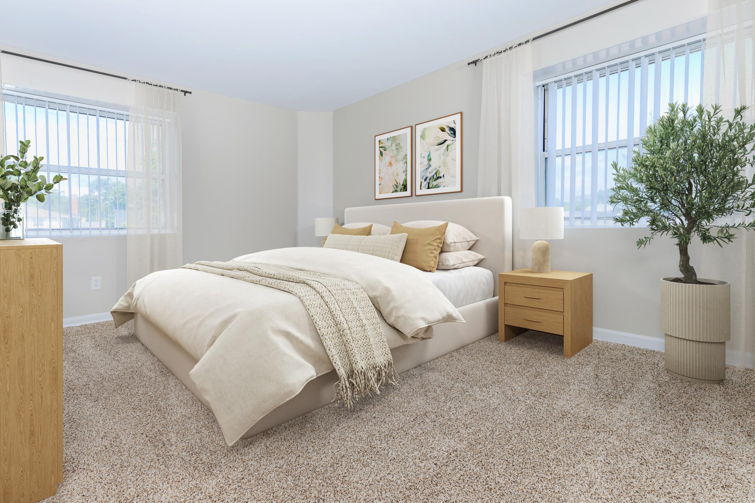 A cozy bedroom featuring a neatly made bed with beige and cream bedding, flanked by two decorative pillows. There are two windows with sheer curtains, allowing natural light to fill the room. A nightstand and a wooden dresser sit beside the bed, and a potted plant adds a touch of greenery to the space.
