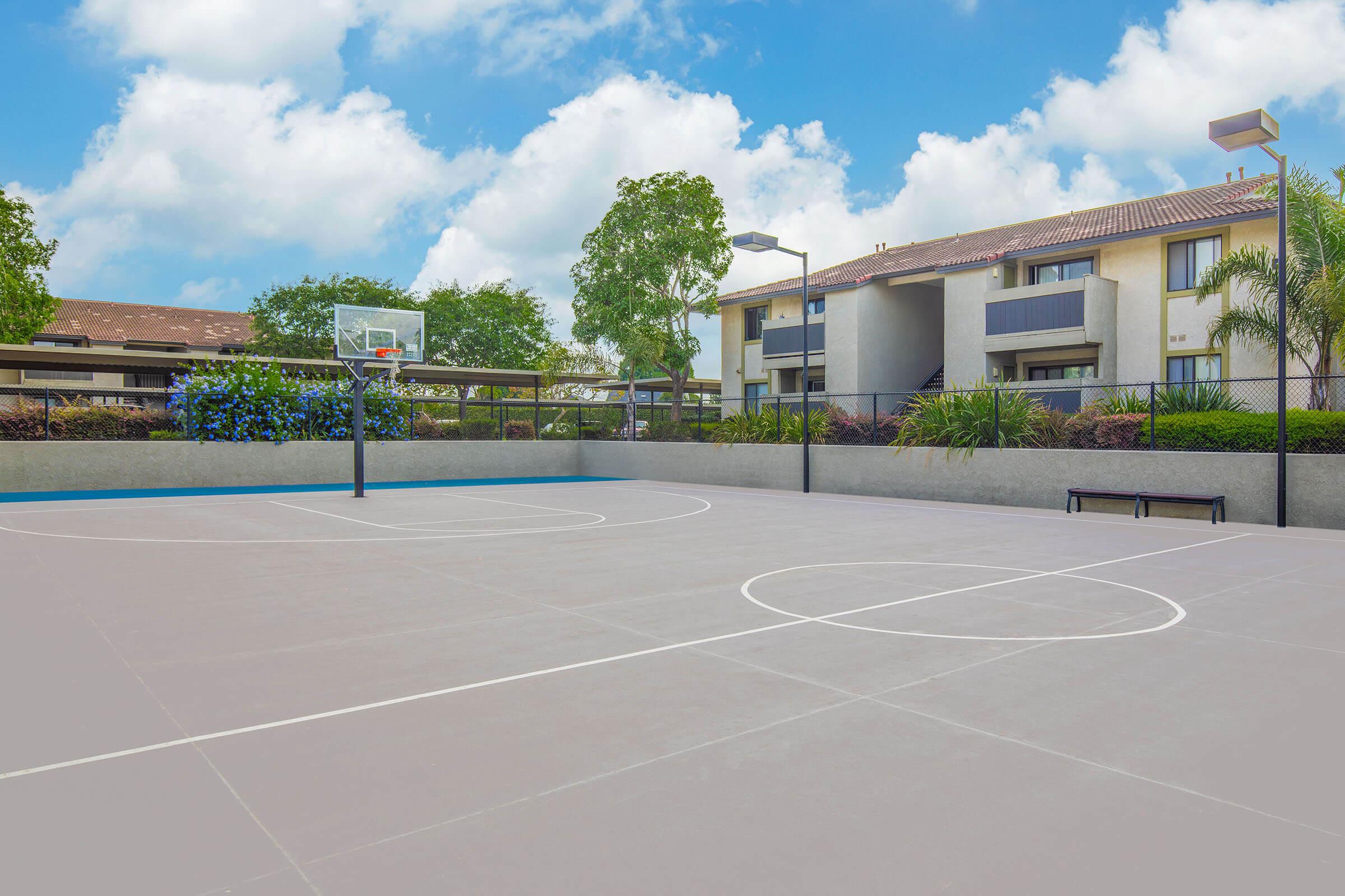 Dog-Friendly Apartments in Santa Maria, CA - Cassia - Basketball Court with a Bench, Blue Skies, and a Basketball Hoop