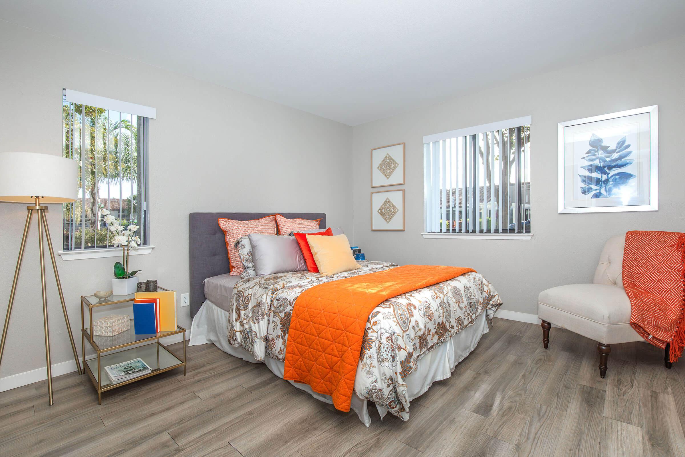 Apartments for Rent Near Santa Maria, CA - Cassia - Bedroom with Decorative Bedding, Large Windows, and a Reading Chair