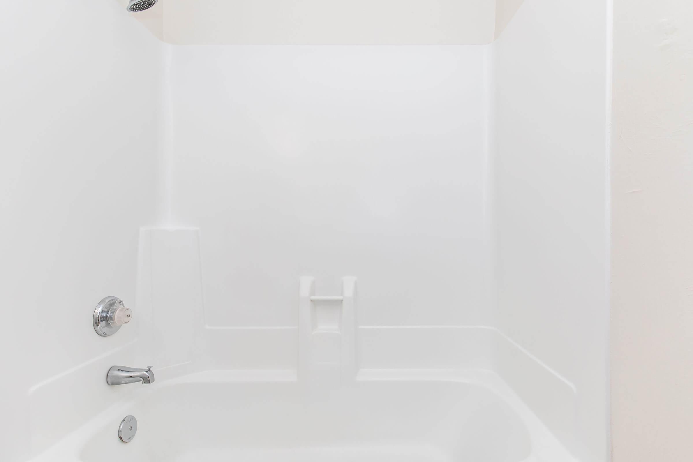 A clean, modern shower stall with white walls and a simple design. The space includes a single faucet and shower head, with no visible accessories or decorations, creating a minimalist look. The overall atmosphere is bright and spacious, emphasizing a fresh and uncluttered feel.