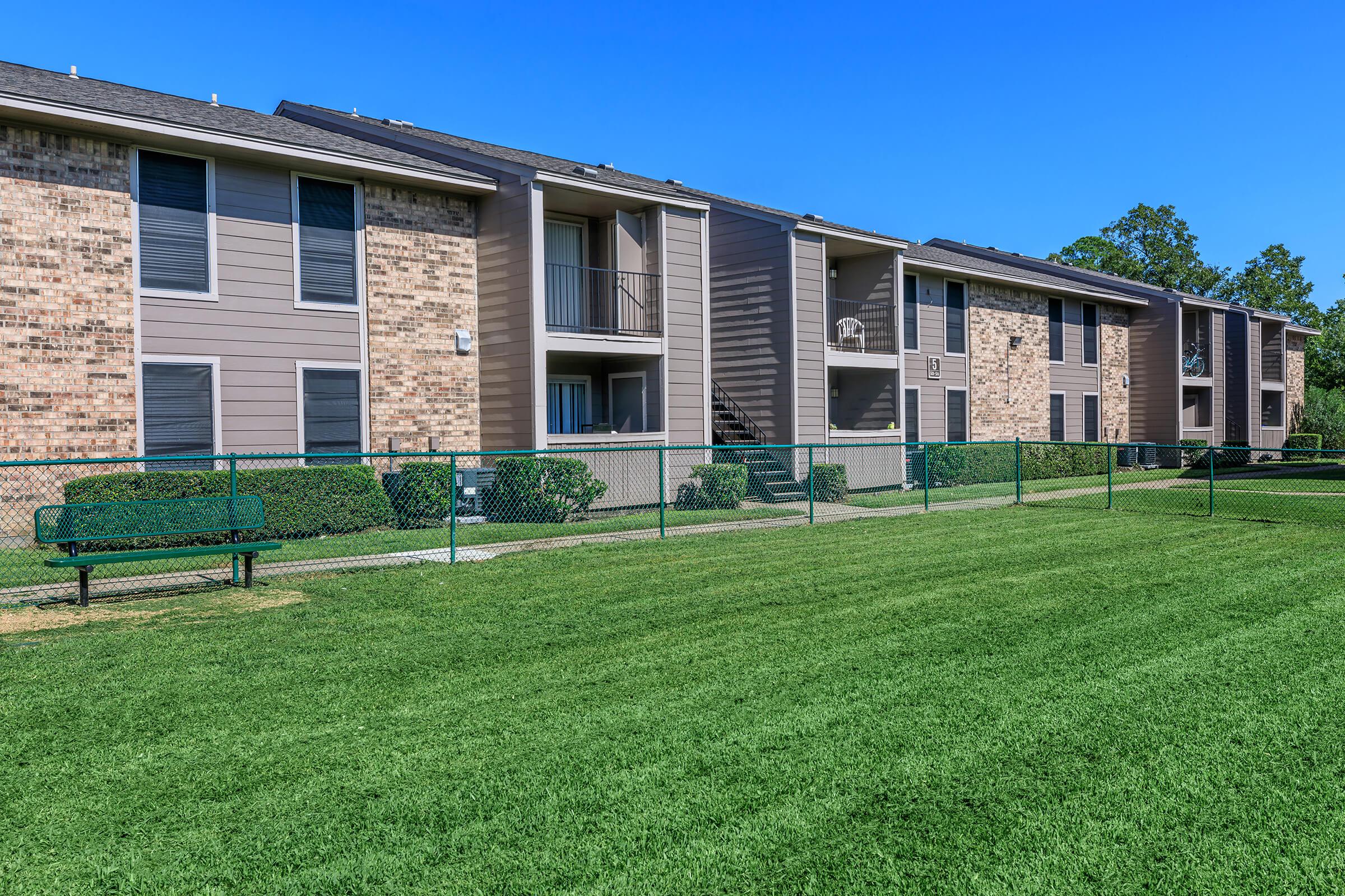 a large brick building with green grass in front of a house