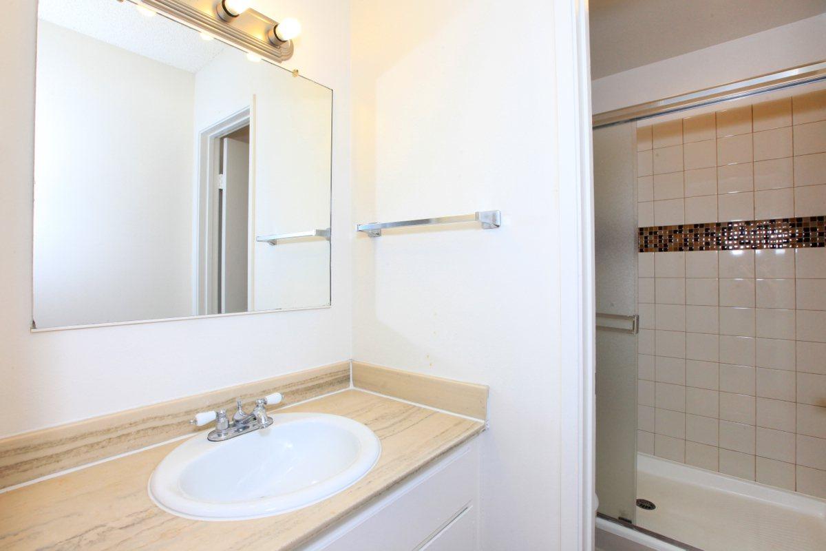 a white sink sitting under a mirror