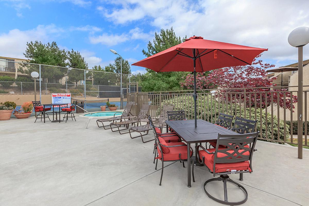 a group of lawn chairs sitting on top of a red umbrella