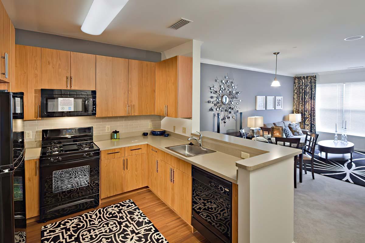 Two-Bedroom Apartments in Long Branch, NJ - The Village at West Long Branch - Kitchen with Brown Cabinets, Black Kitchen Appliances, and a High Countertop