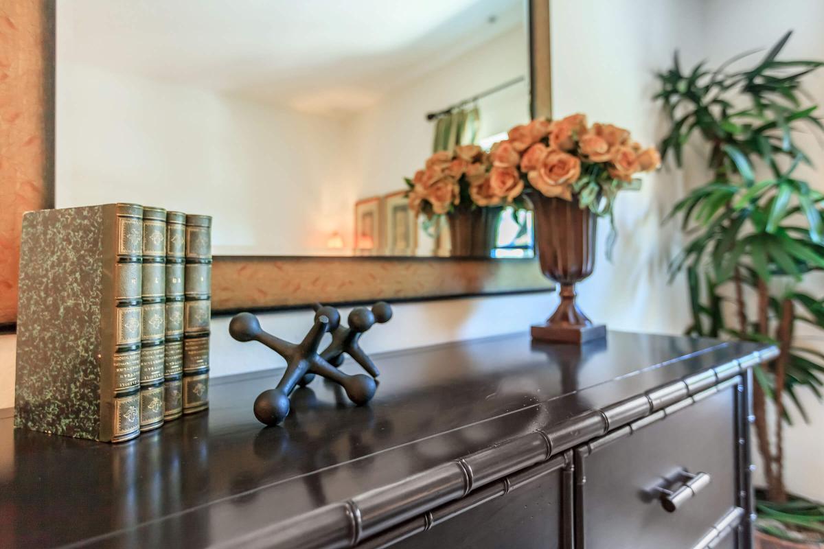 a room filled with furniture and vase of flowers on a kitchen counter