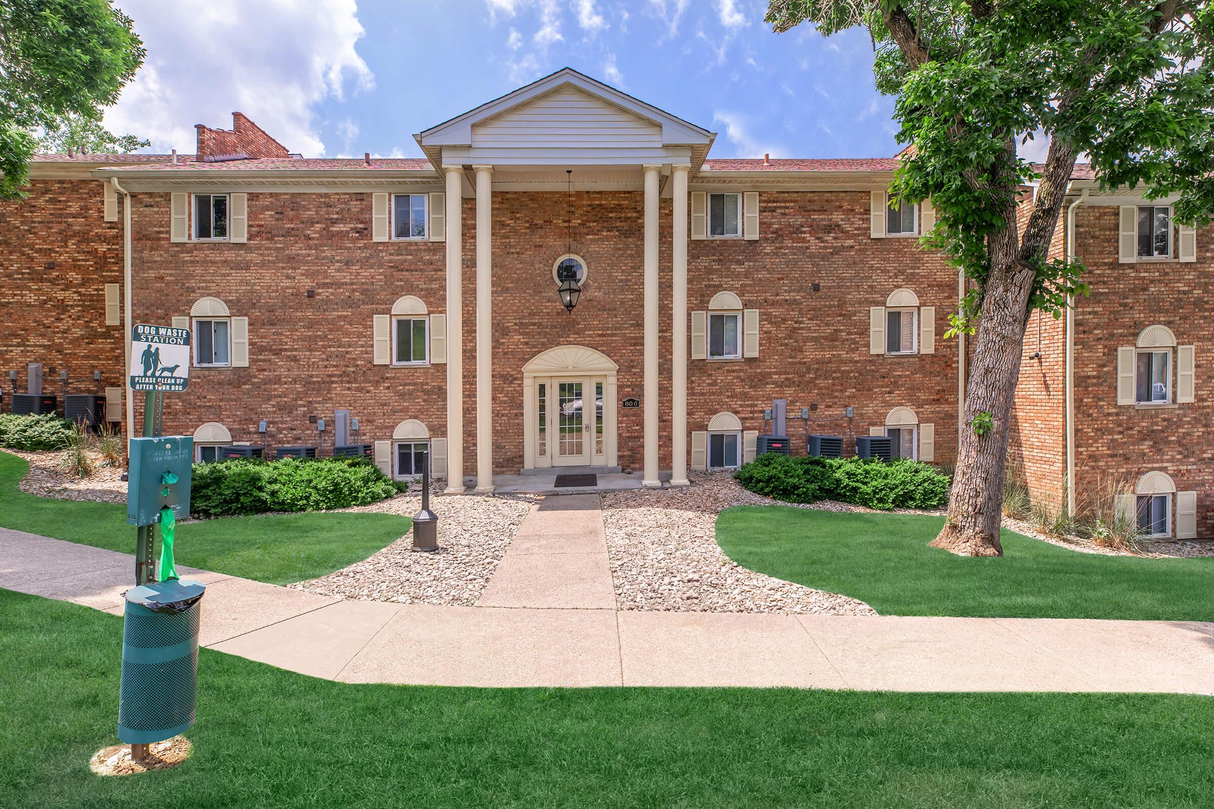 a house with a lawn in front of a brick building