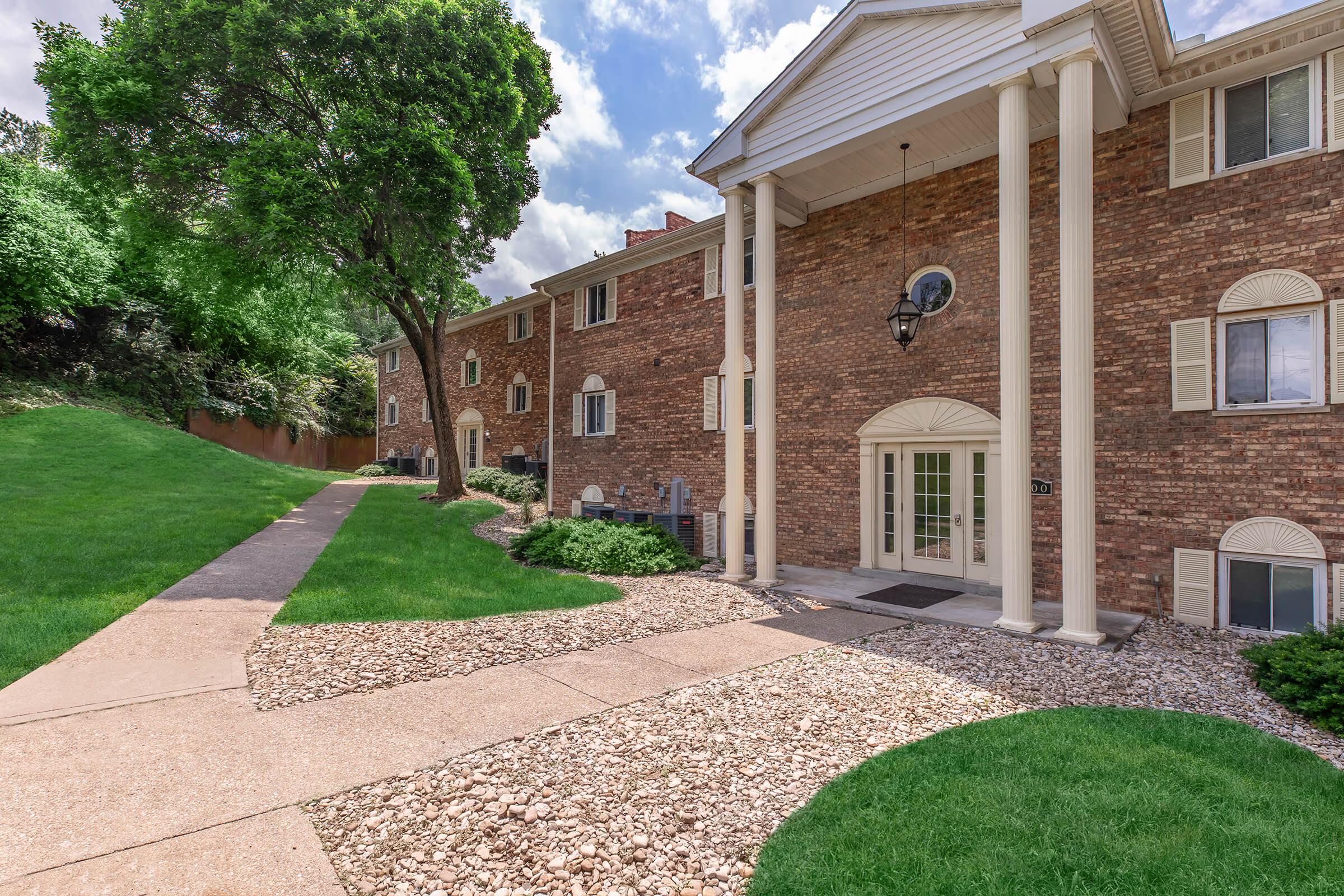 a large brick building with grass in front of a house