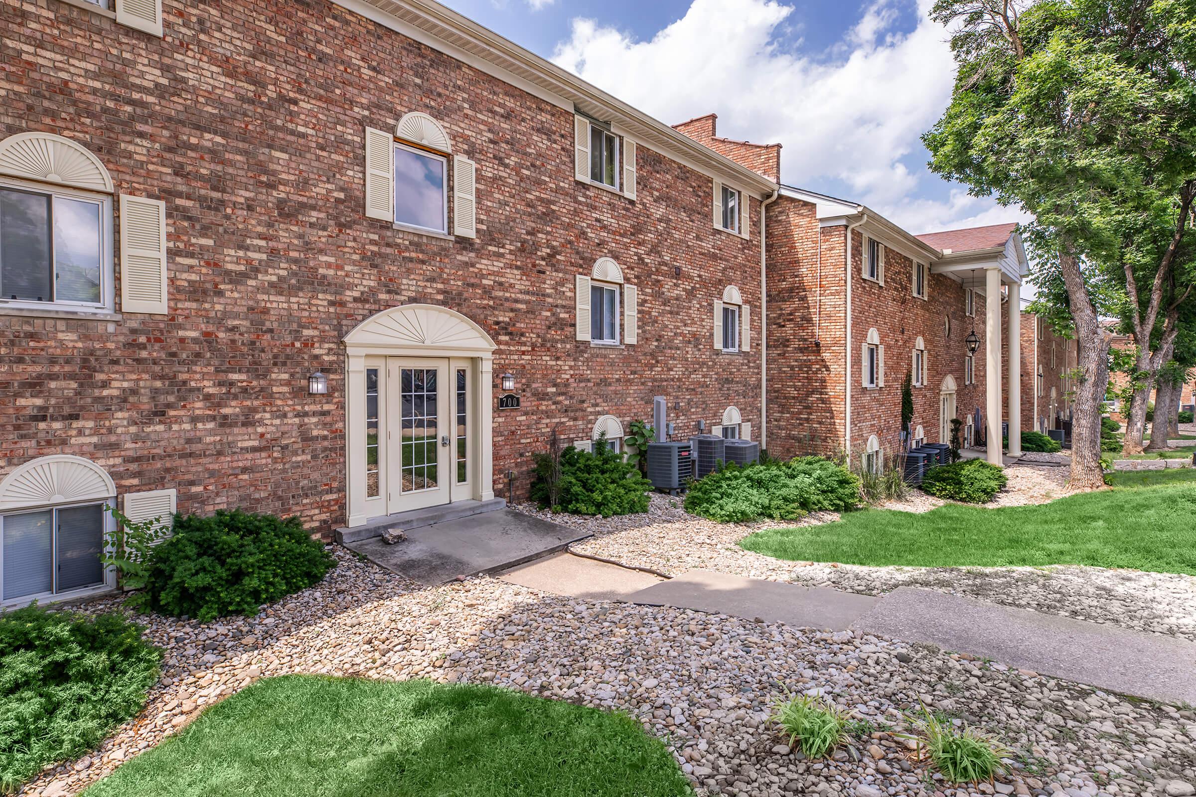 a large brick building with grass in front of a house