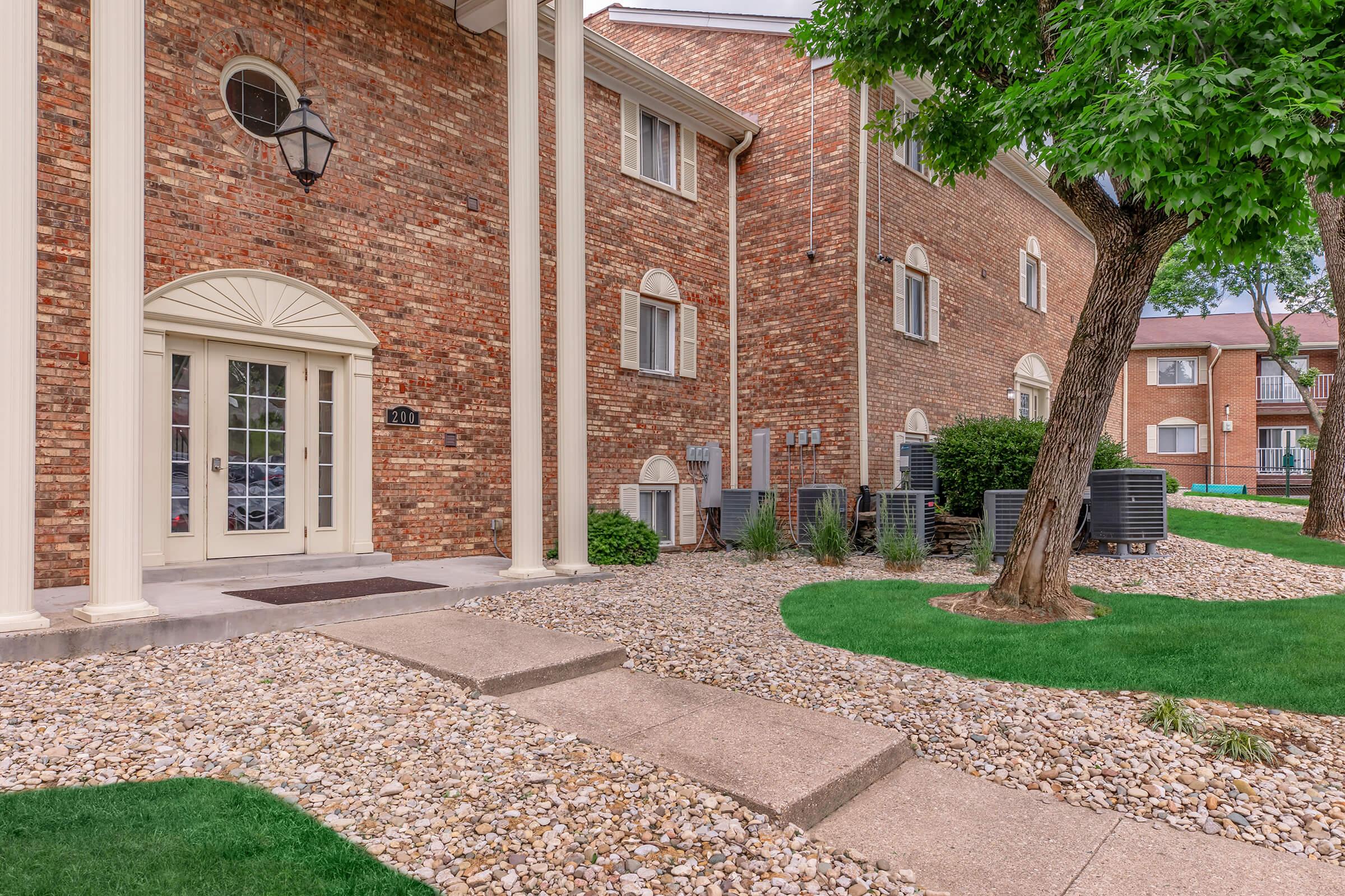 a large brick building with grass in front of a house