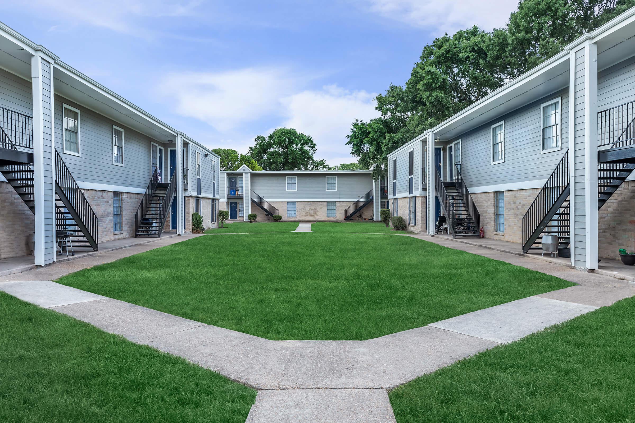 a house with a lawn in front of a brick building