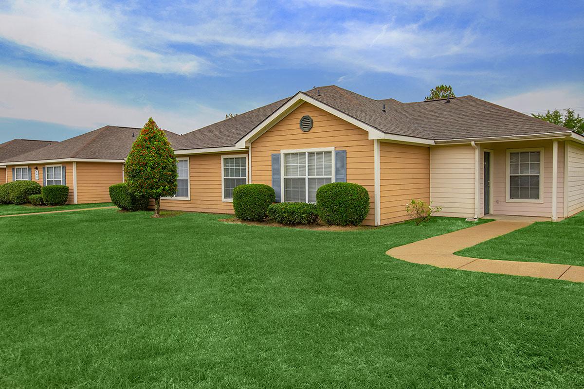 a large brick building with green grass in front of a house