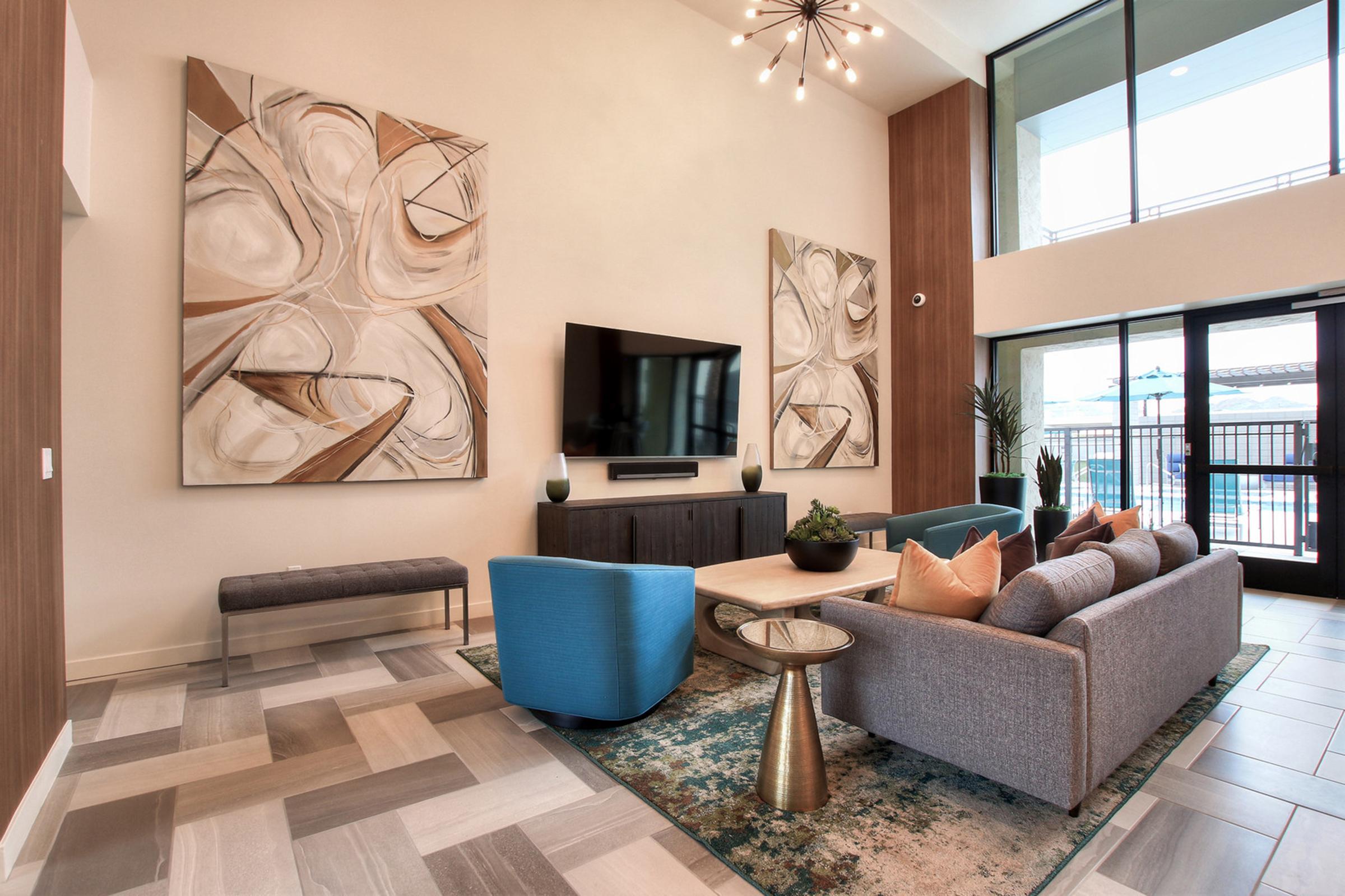 Modern living room with high ceilings featuring two large abstract paintings on the walls. 