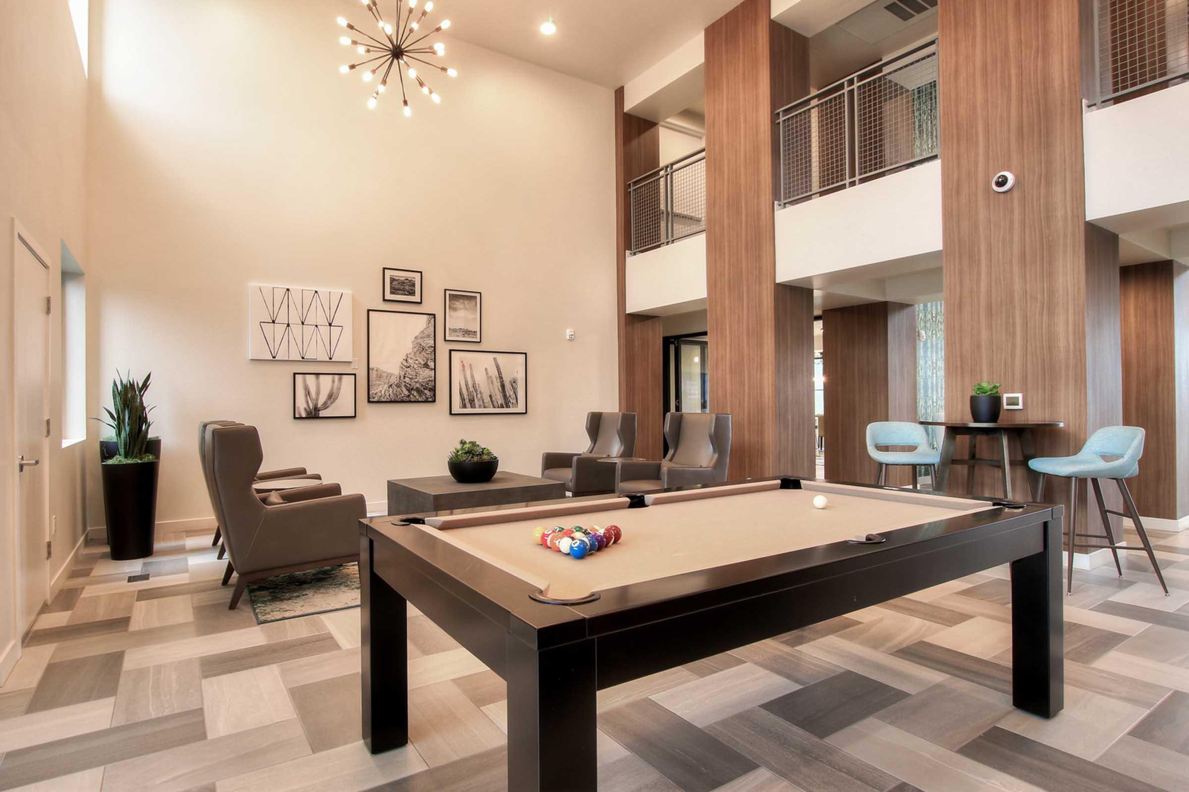 Modern lounge area featuring a pool table, two armchairs, and a coffee table. 