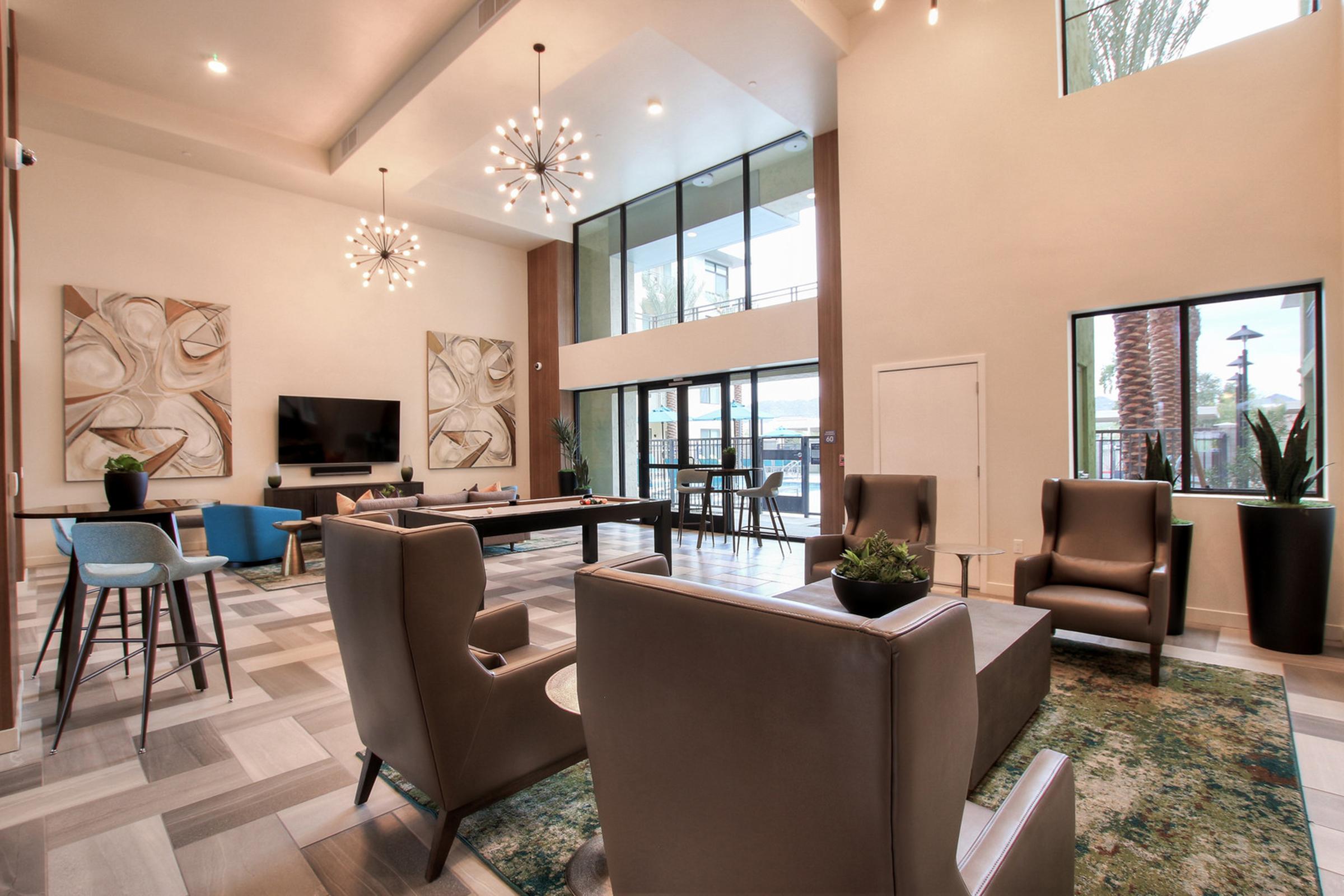 A modern lounge area featuring stylish furniture, including two armchairs and a pool table.