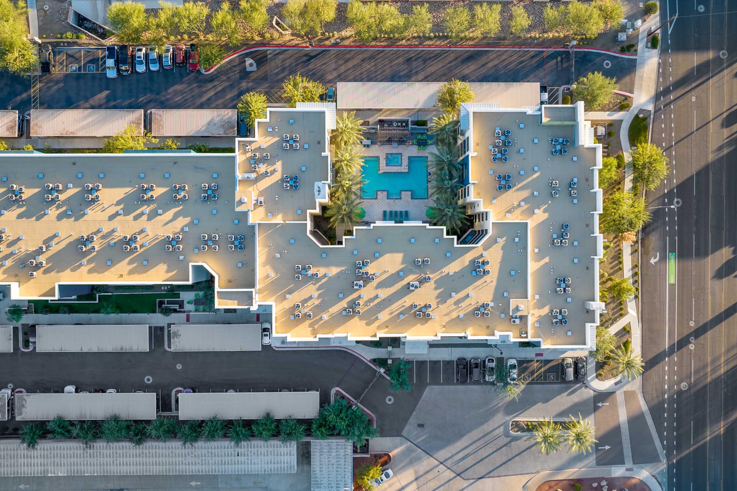 Aerial view of a large building complex featuring a rooftop area with numerous blue tables and chairs.