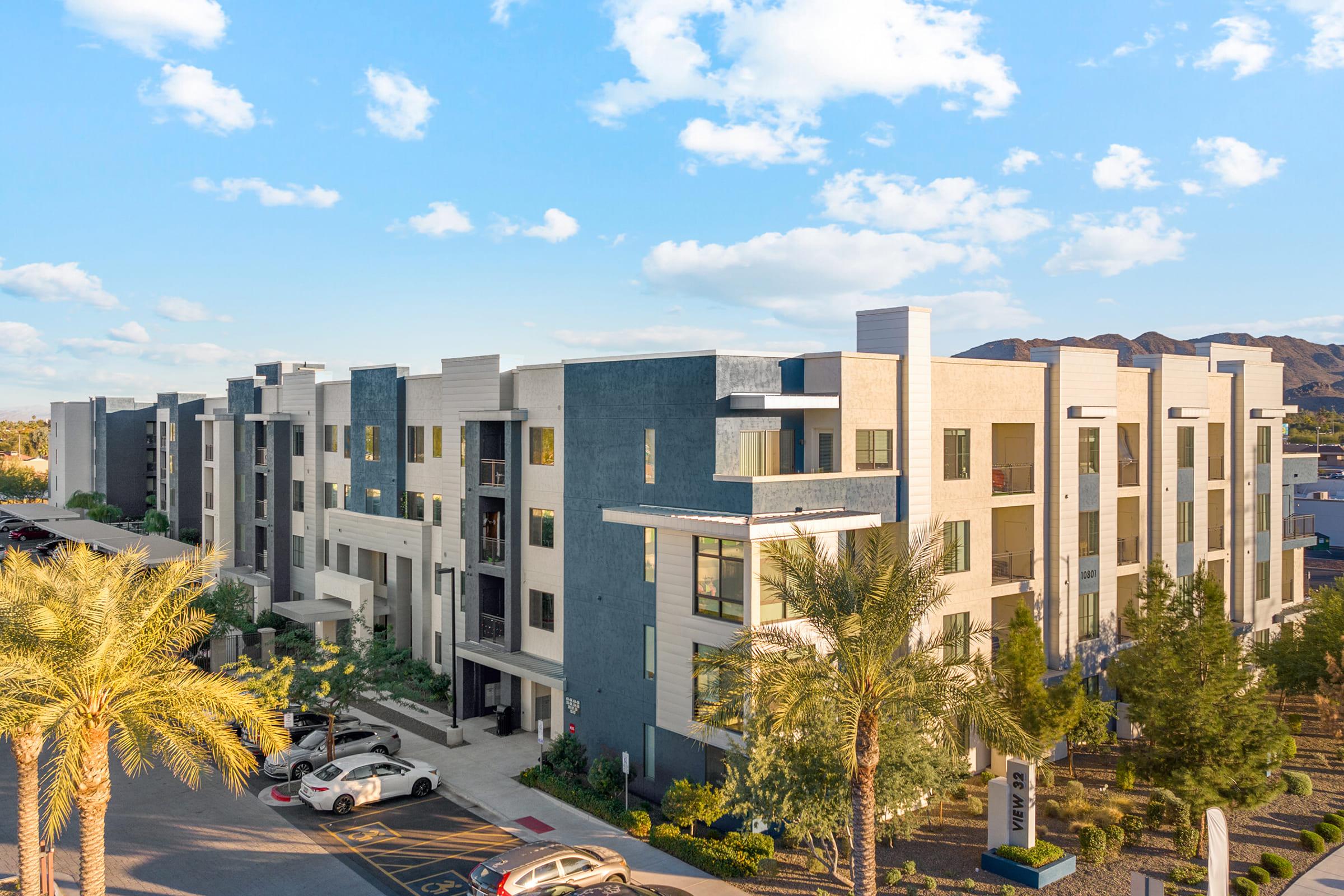 A modern multi-story apartment building featuring a mix of light and dark exterior colors. 