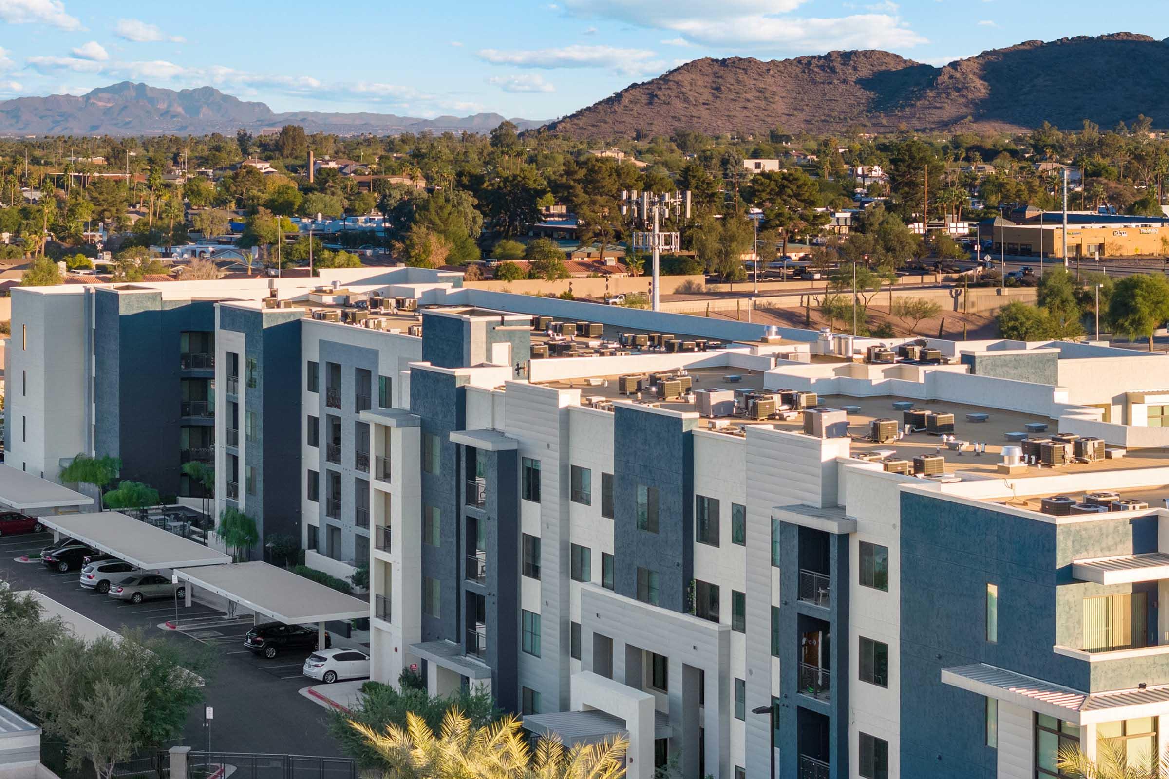 Aerial view of a modern apartment complex with multiple stories, featuring a mix of blue and white facades. 