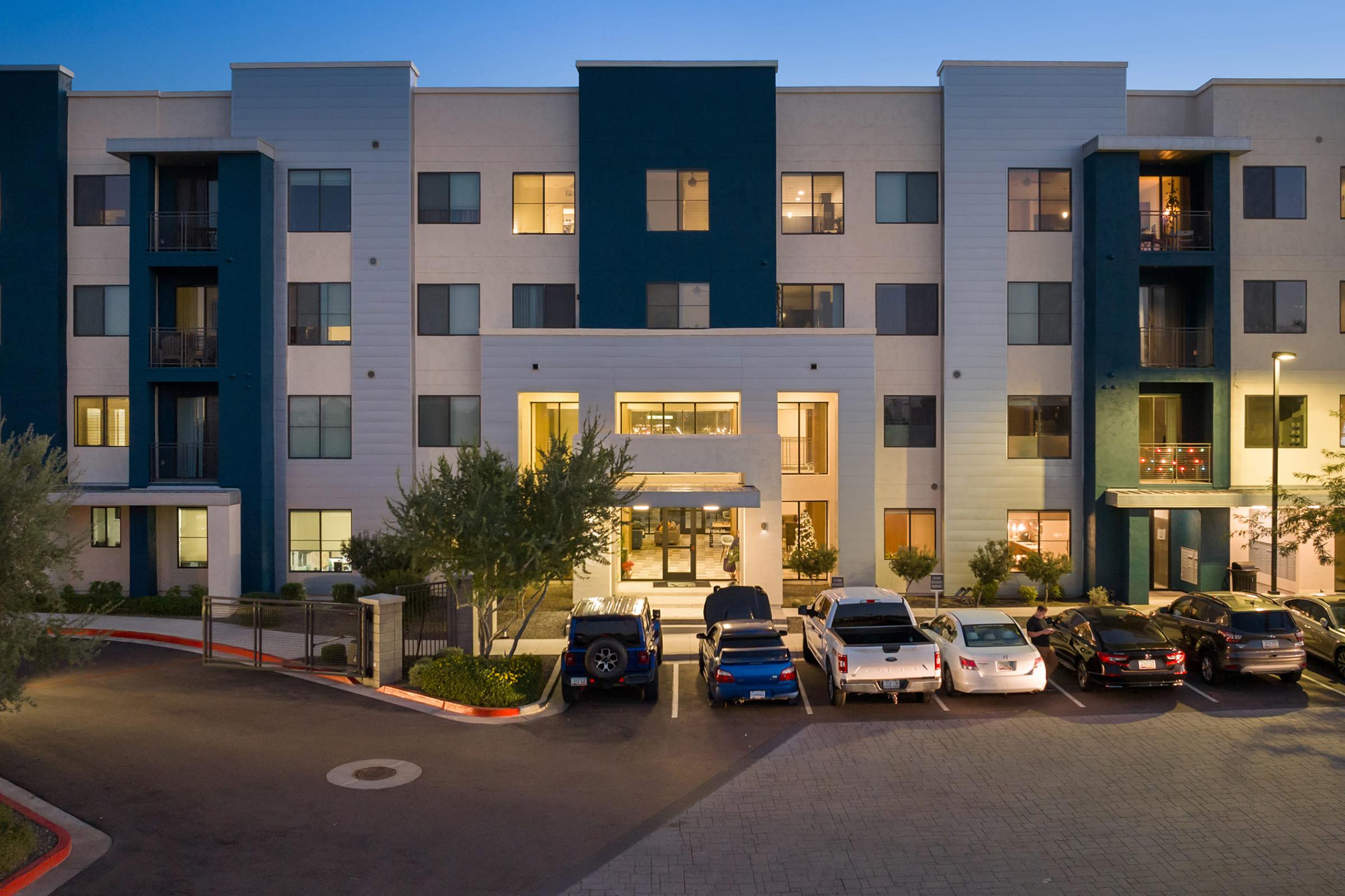  Modern multi-story apartment building with a sleek exterior design featuring a combination of light and dark colors. 