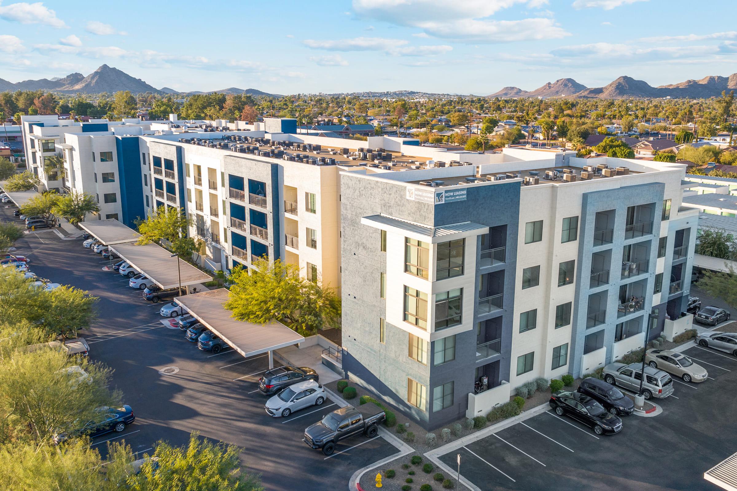 Aerial view of a modern apartment complex with multiple stories, featuring a mix of light and dark-colored exterior.