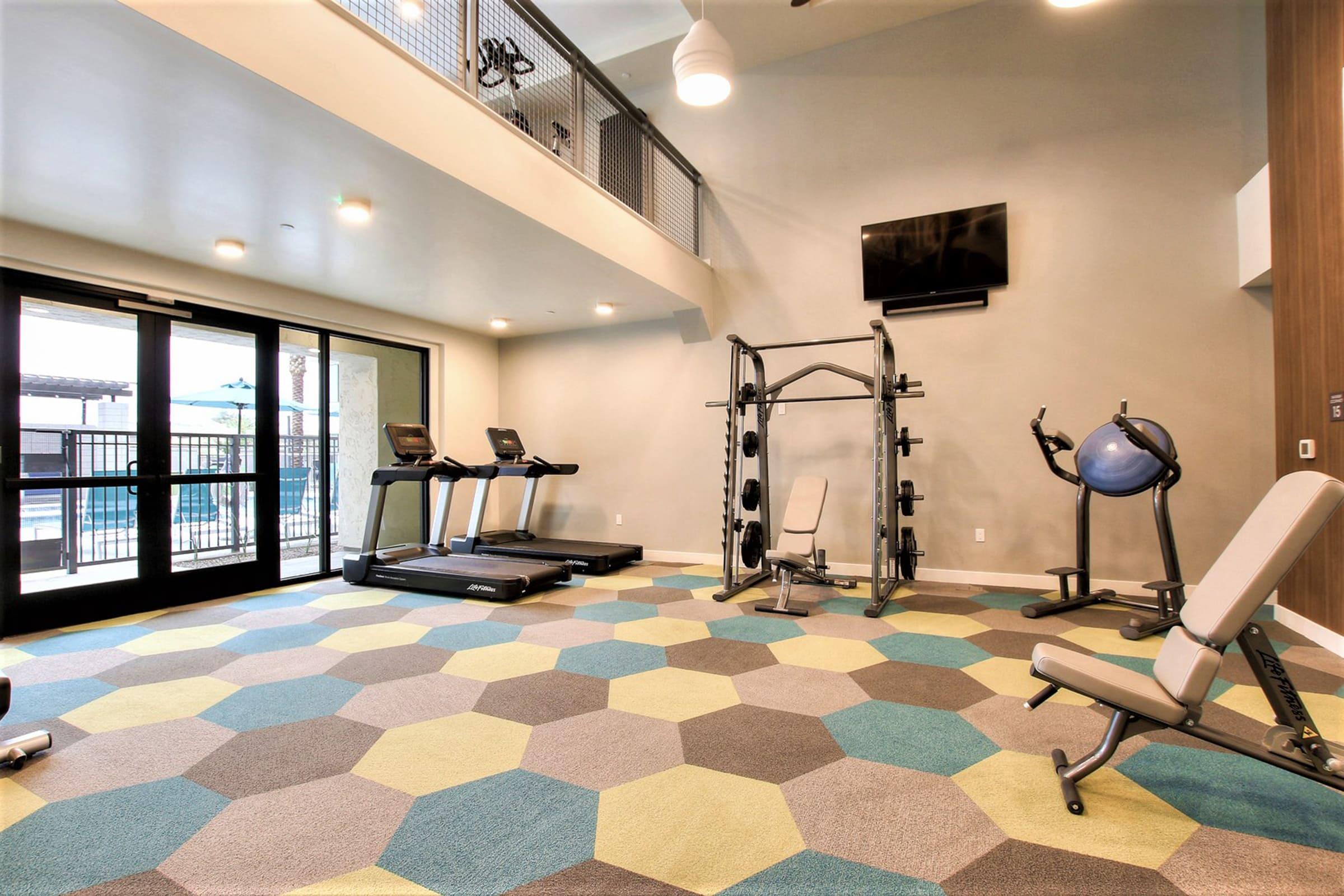 A modern gym interior featuring treadmills, a multi-gym weight machine, and exercise equipment. 