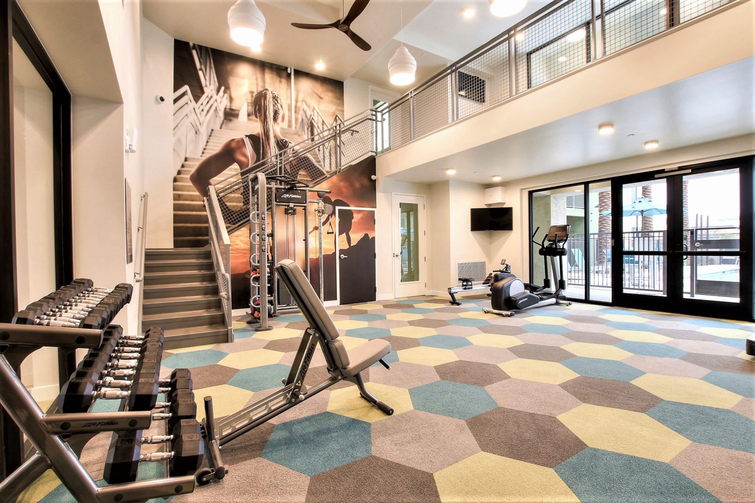 A spacious gym area featuring various exercise equipment, including free weights and a bench.