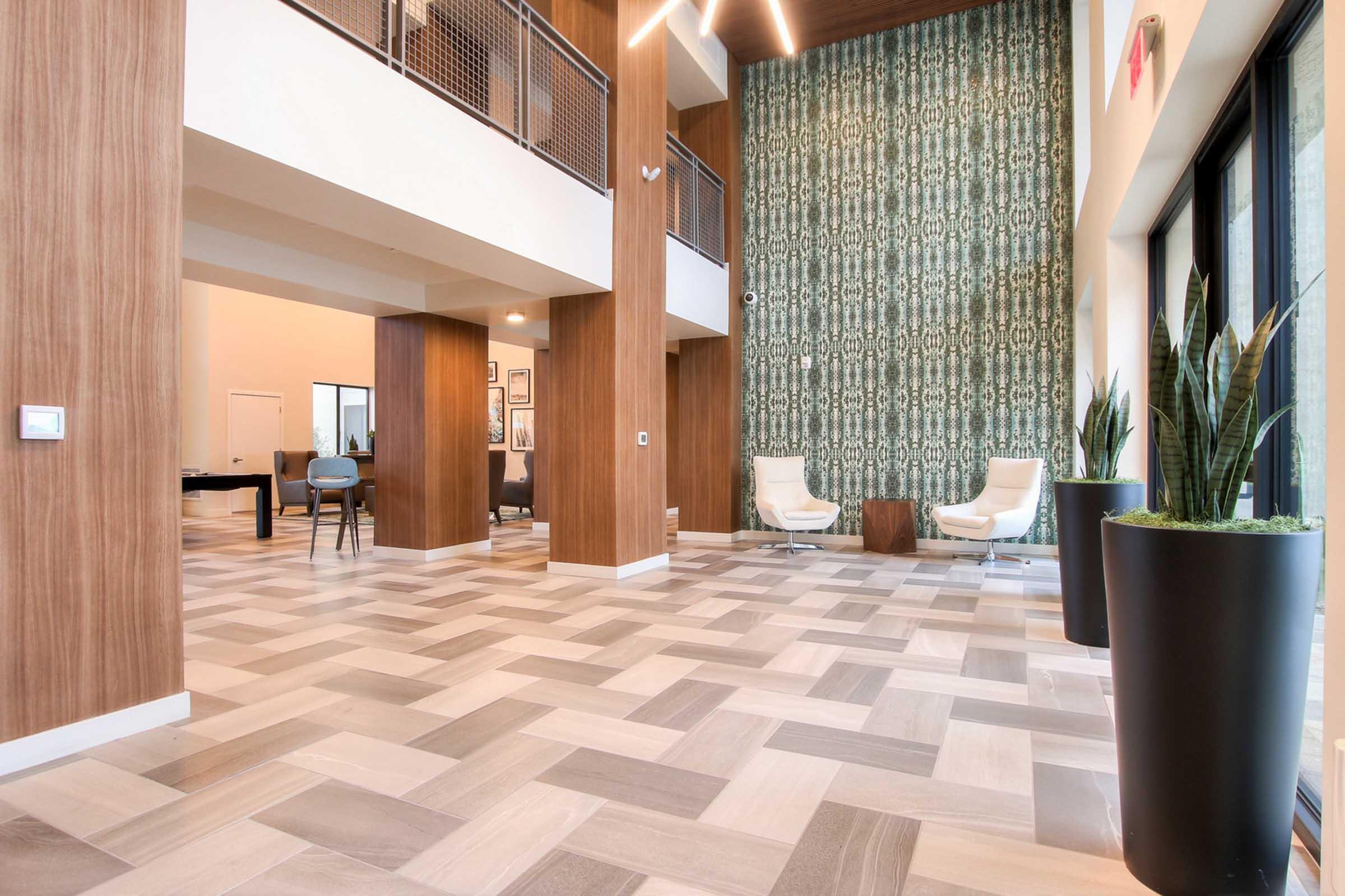 A modern lobby with a stylish design featuring a patterned accent wall, wooden pillars, and large windows.