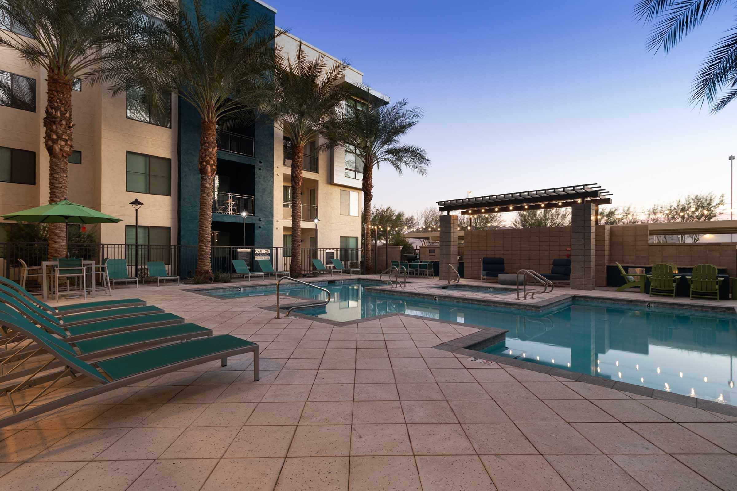  A serene pool area surrounded by palm trees and lounge chairs.