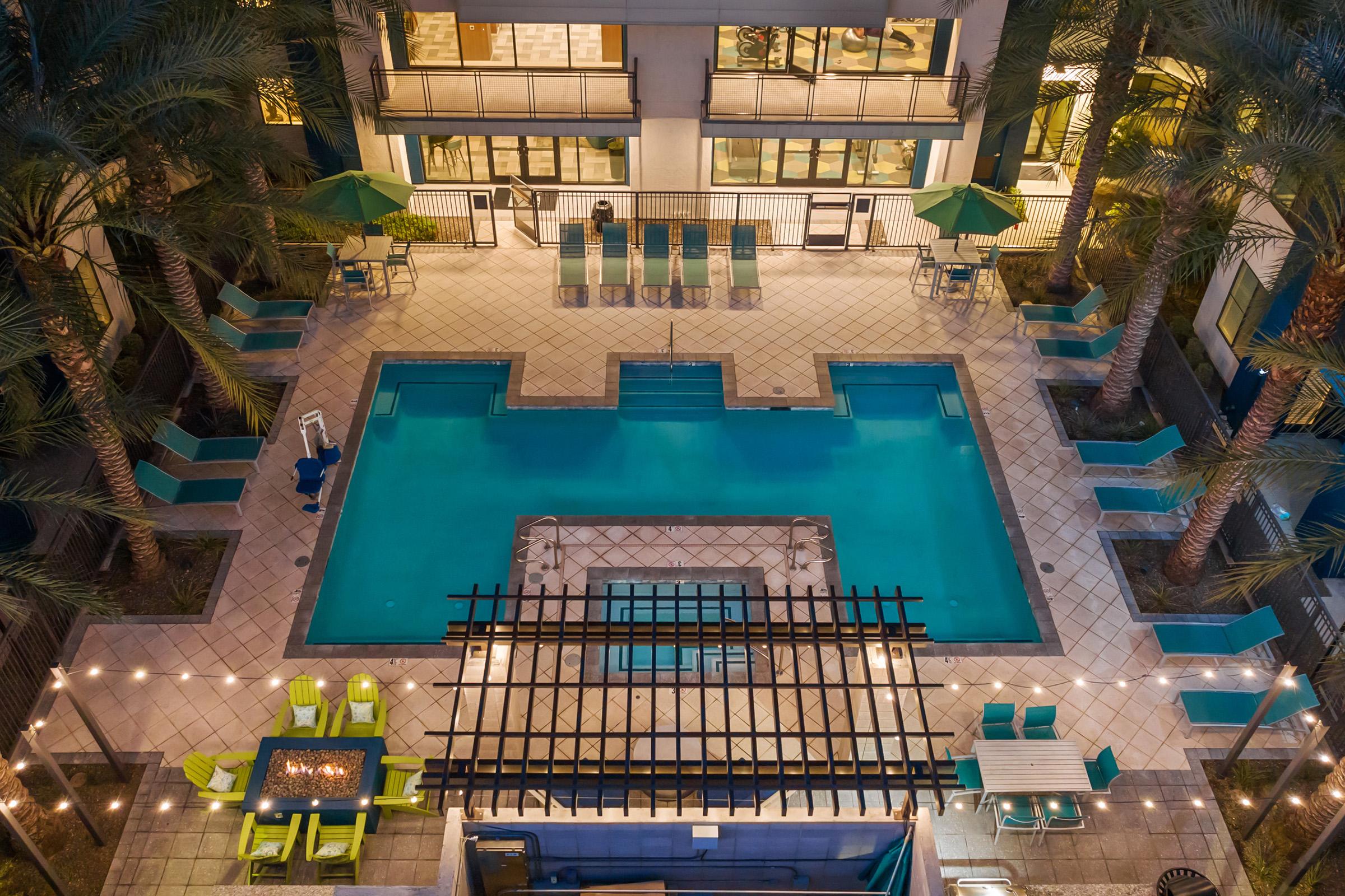 Aerial view of a modern swimming pool area surrounded by palm trees. 