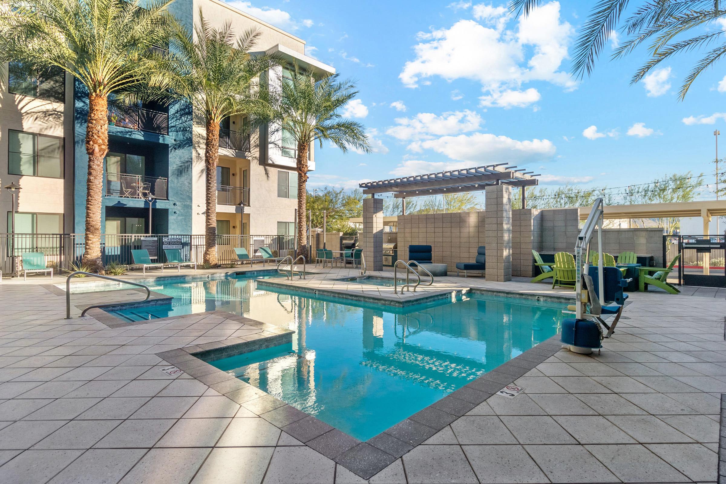 A tranquil pool area featuring an inviting blue pool surrounded by palm trees and comfortable lounge chairs. 