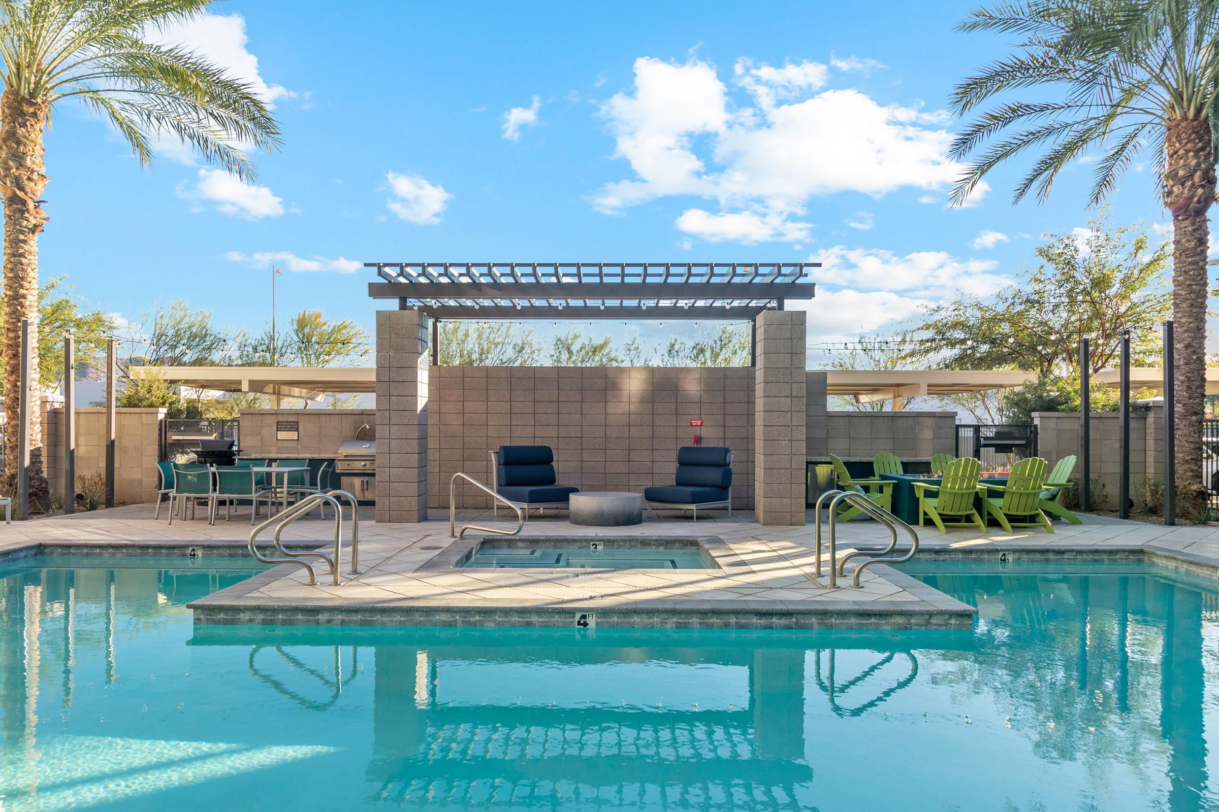 Swimming pool area featuring palm trees, lounge chairs, and a shaded seating area with a pergola.