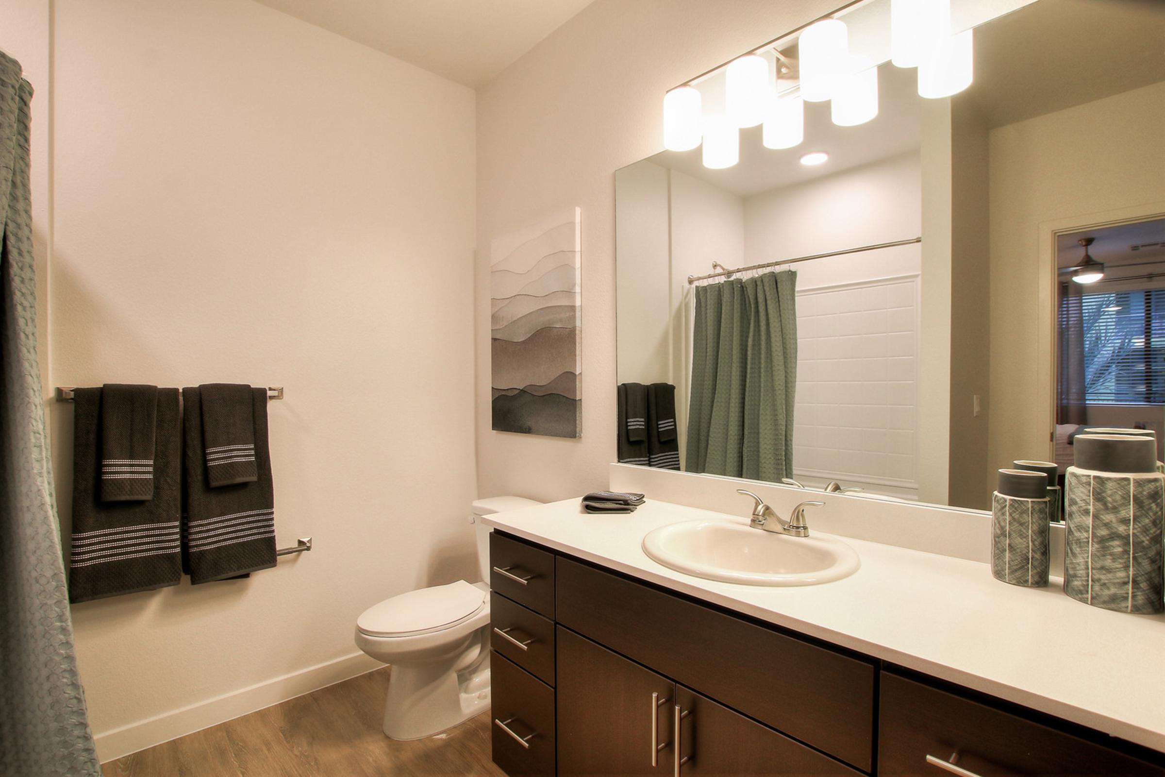 A modern bathroom featuring a large mirror above a white sink with a faucet. 