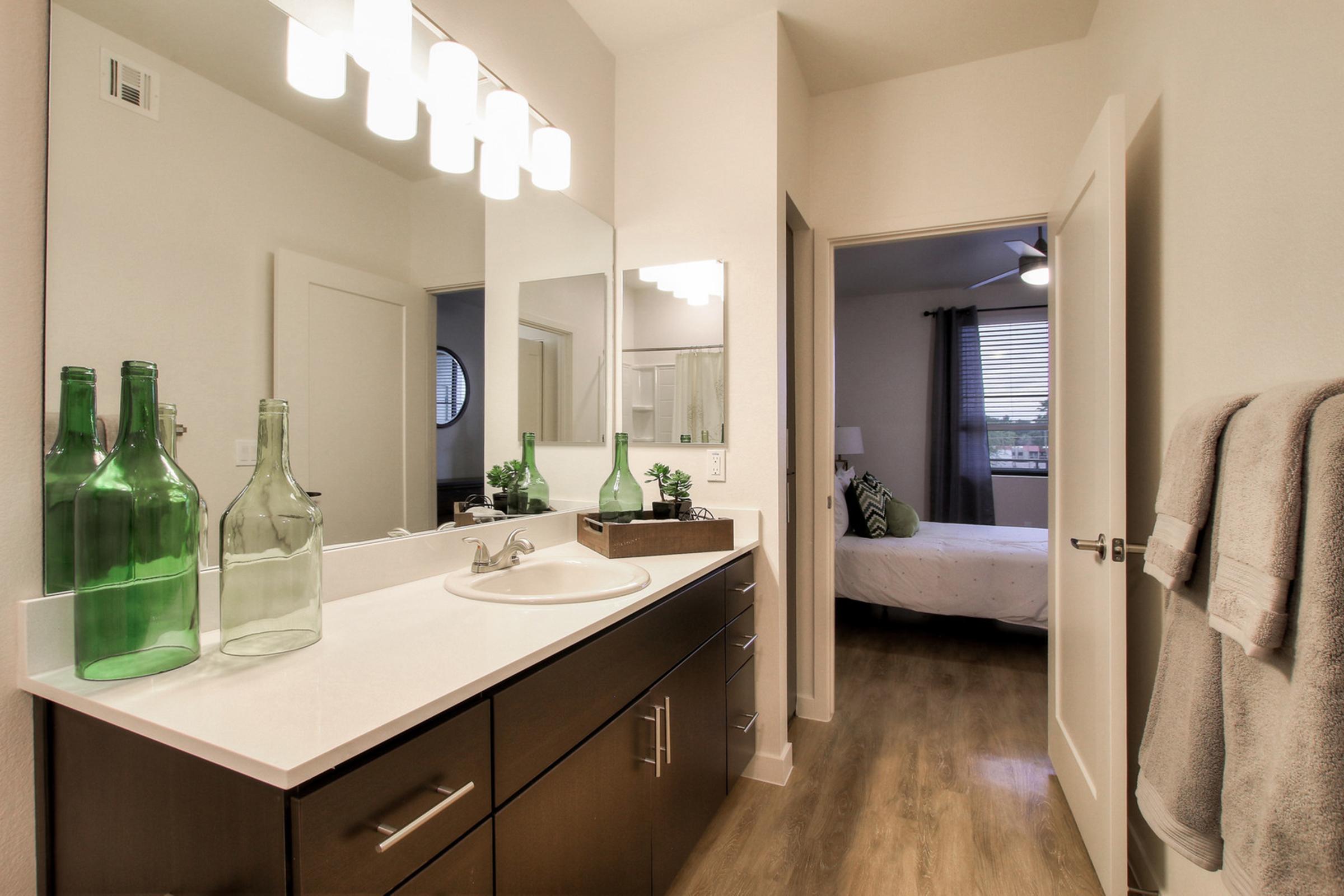 A modern bathroom featuring a sleek vanity with a white countertop, sink, and dark wooden cabinets.
