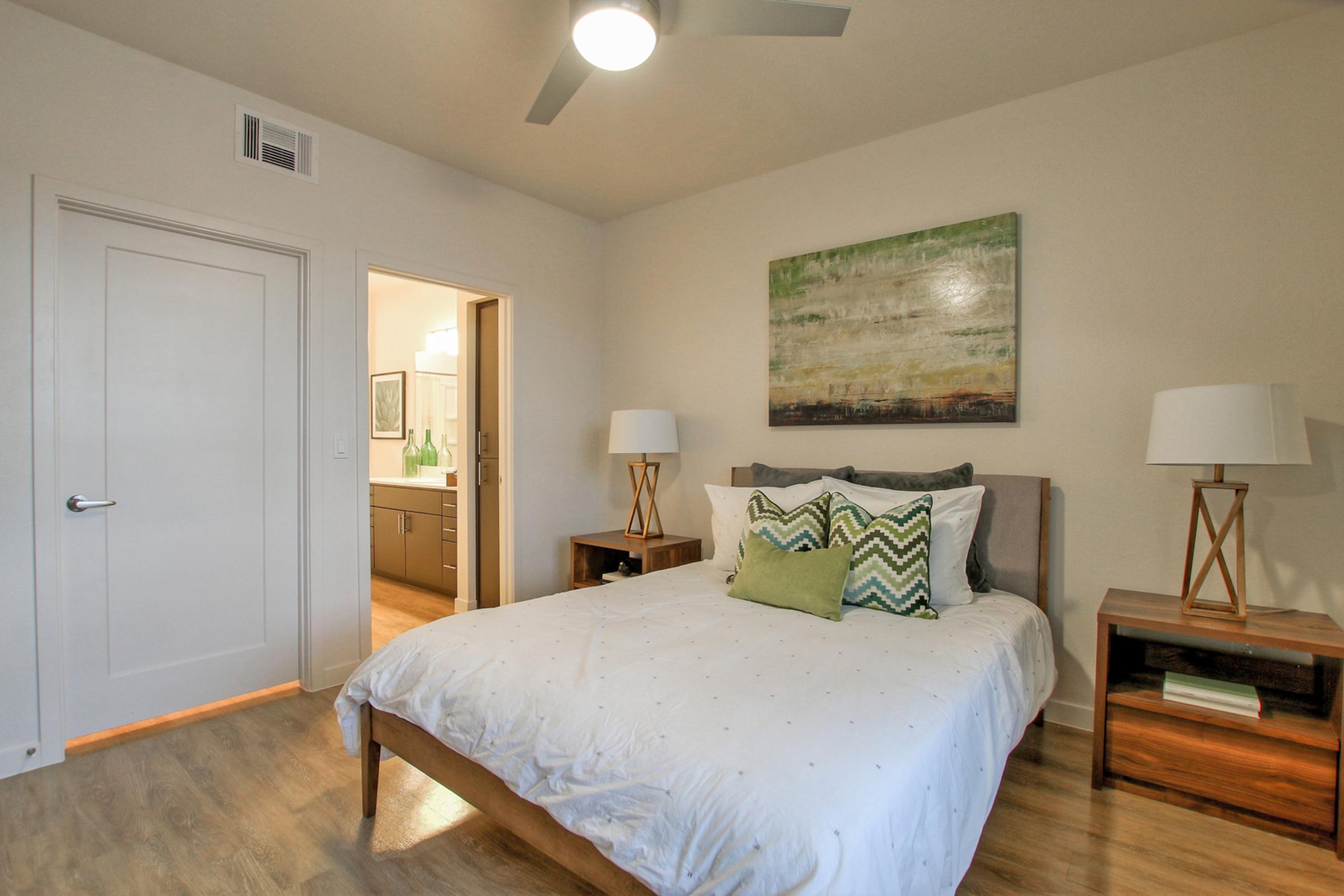  A modern bedroom featuring a queen-sized bed with white bedding and decorative pillows. 