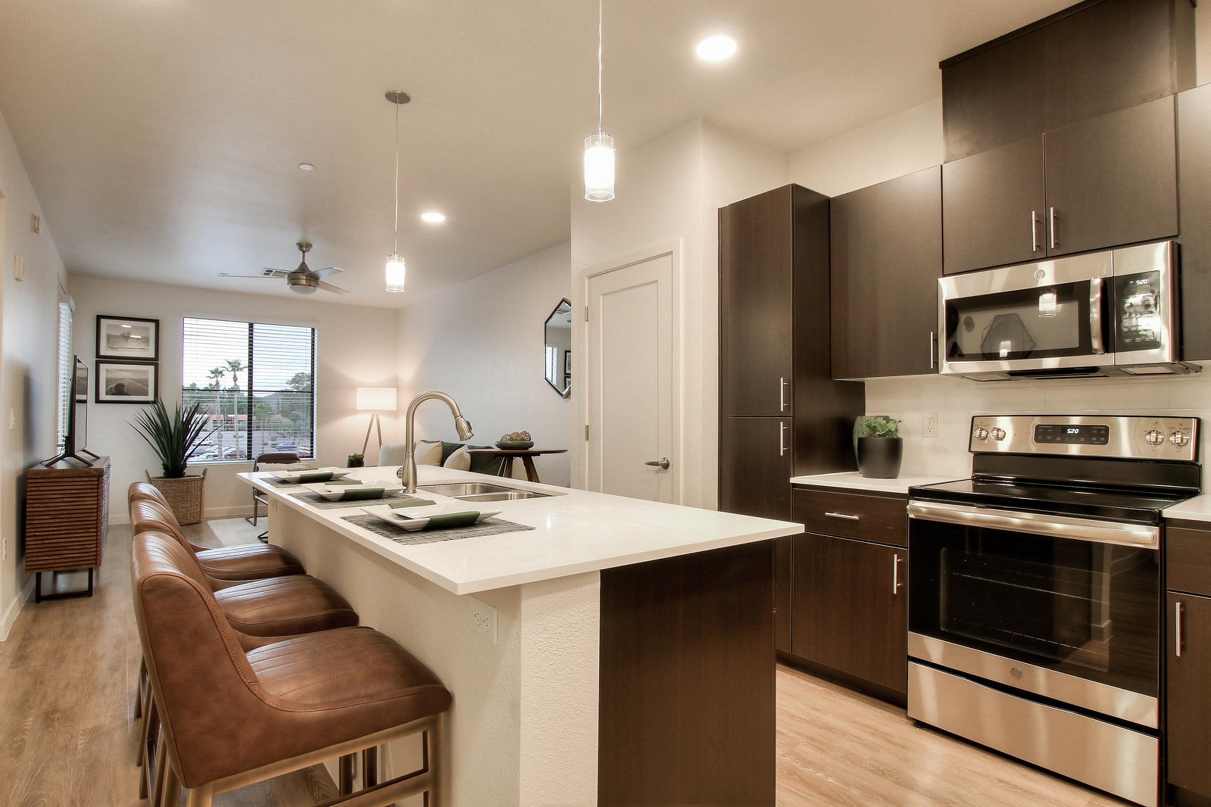 Modern kitchen featuring a sleek design with dark cabinetry, stainless steel appliances, and a central island with bar stools.