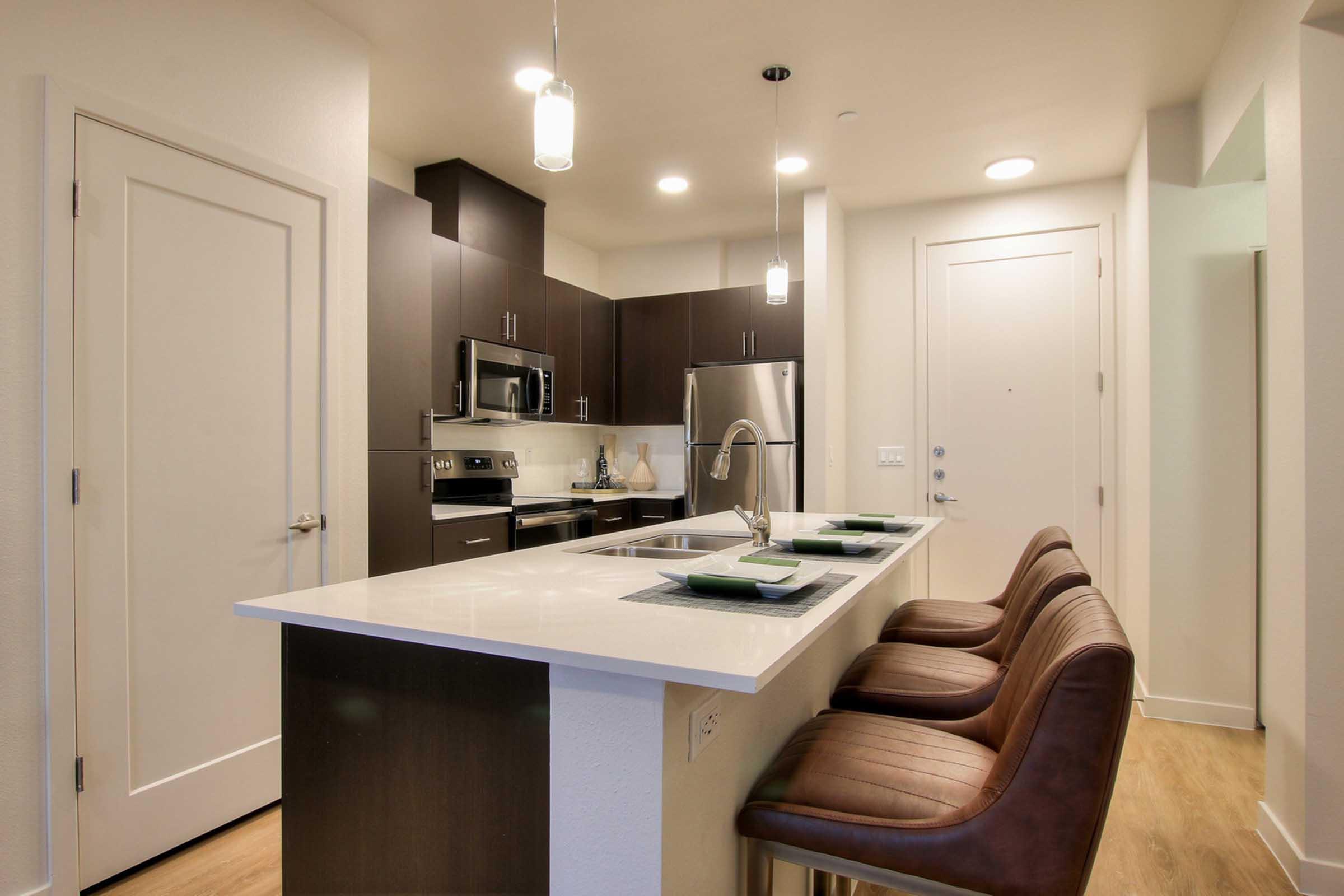 Modern kitchen featuring dark wood cabinetry, stainless steel appliances, and a white countertop.