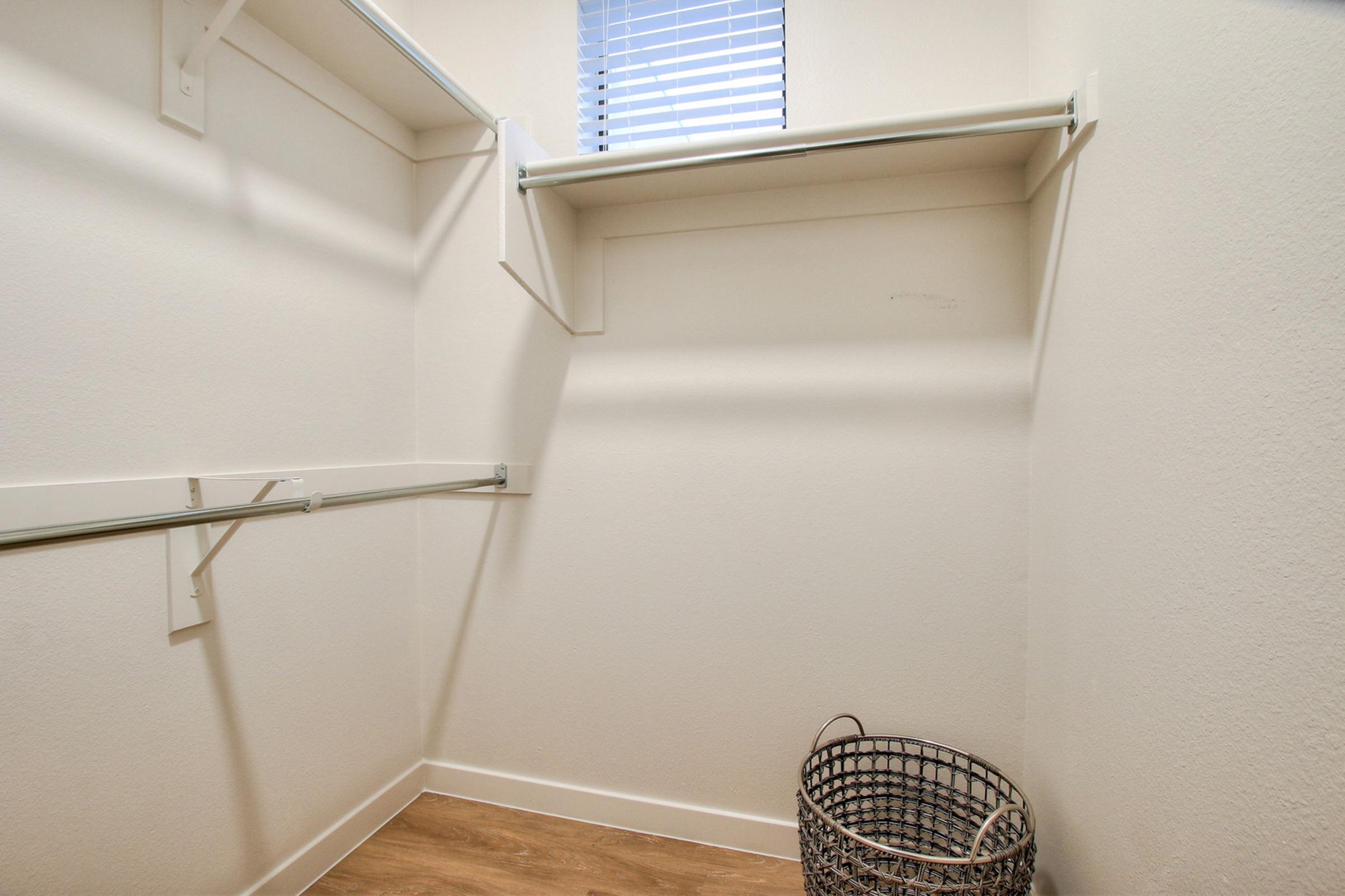 Empty closet with white walls, two shelves on the left side, and a single hanging rod. 