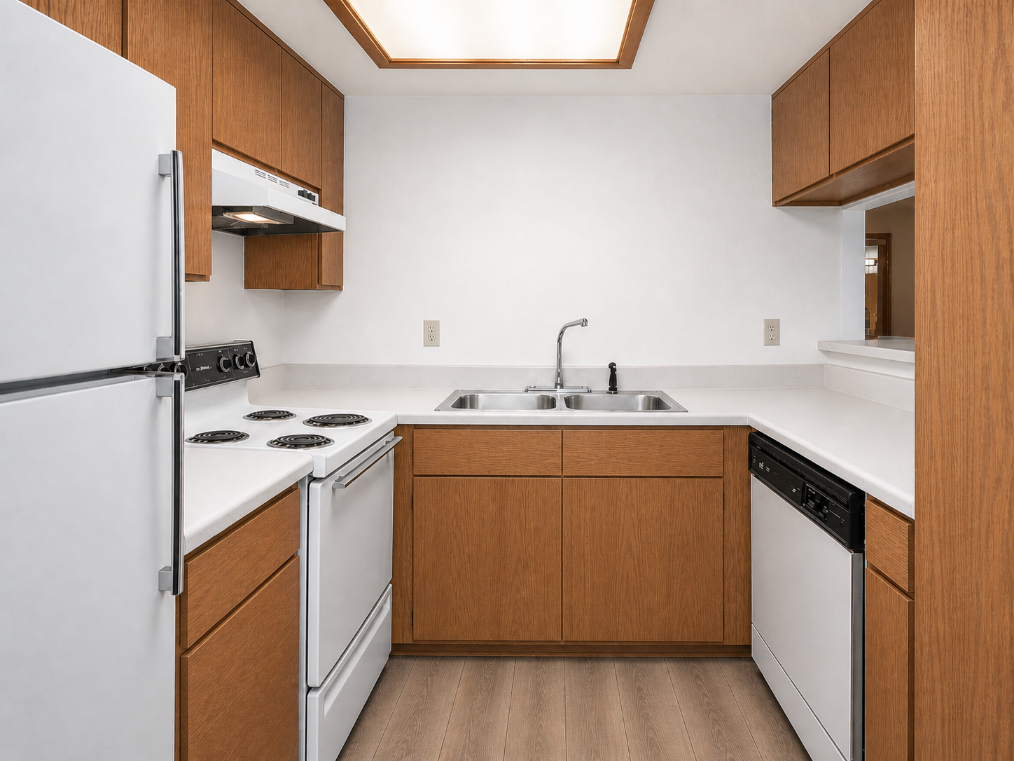A modern kitchen featuring wooden cabinetry, white countertops, and essential appliances. There is a white refrigerator, a stove with four burners, a sink with a faucet, and a dishwasher. The kitchen has a bright, clean aesthetic with light-colored walls and a wooden floor.