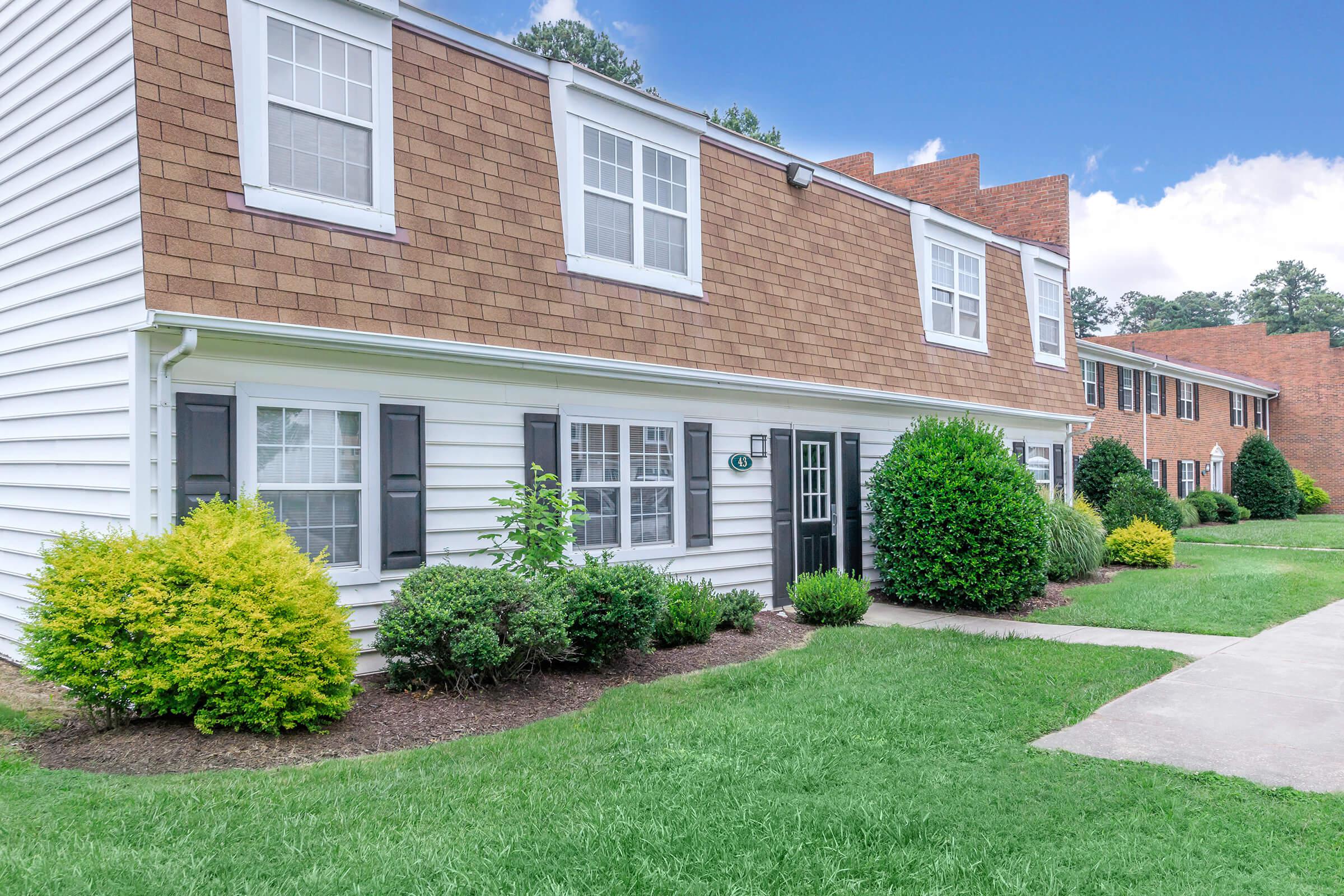 a large brick building with green grass in front of a house