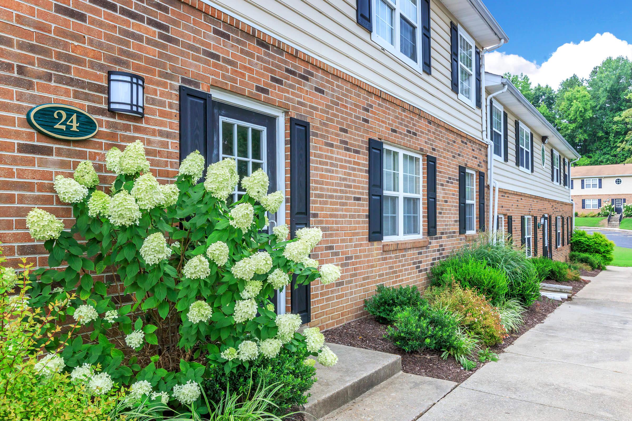 a house with bushes in front of a brick building