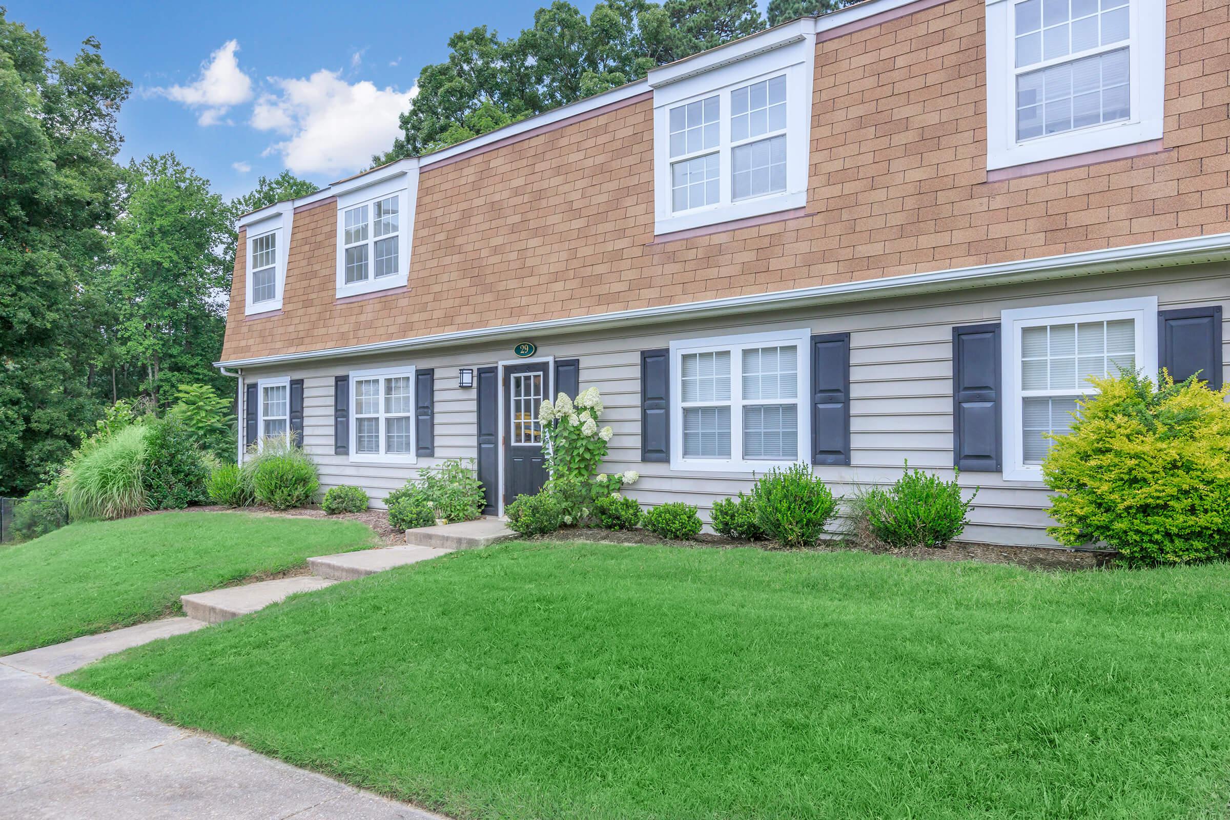 a large brick building with grass in front of a house