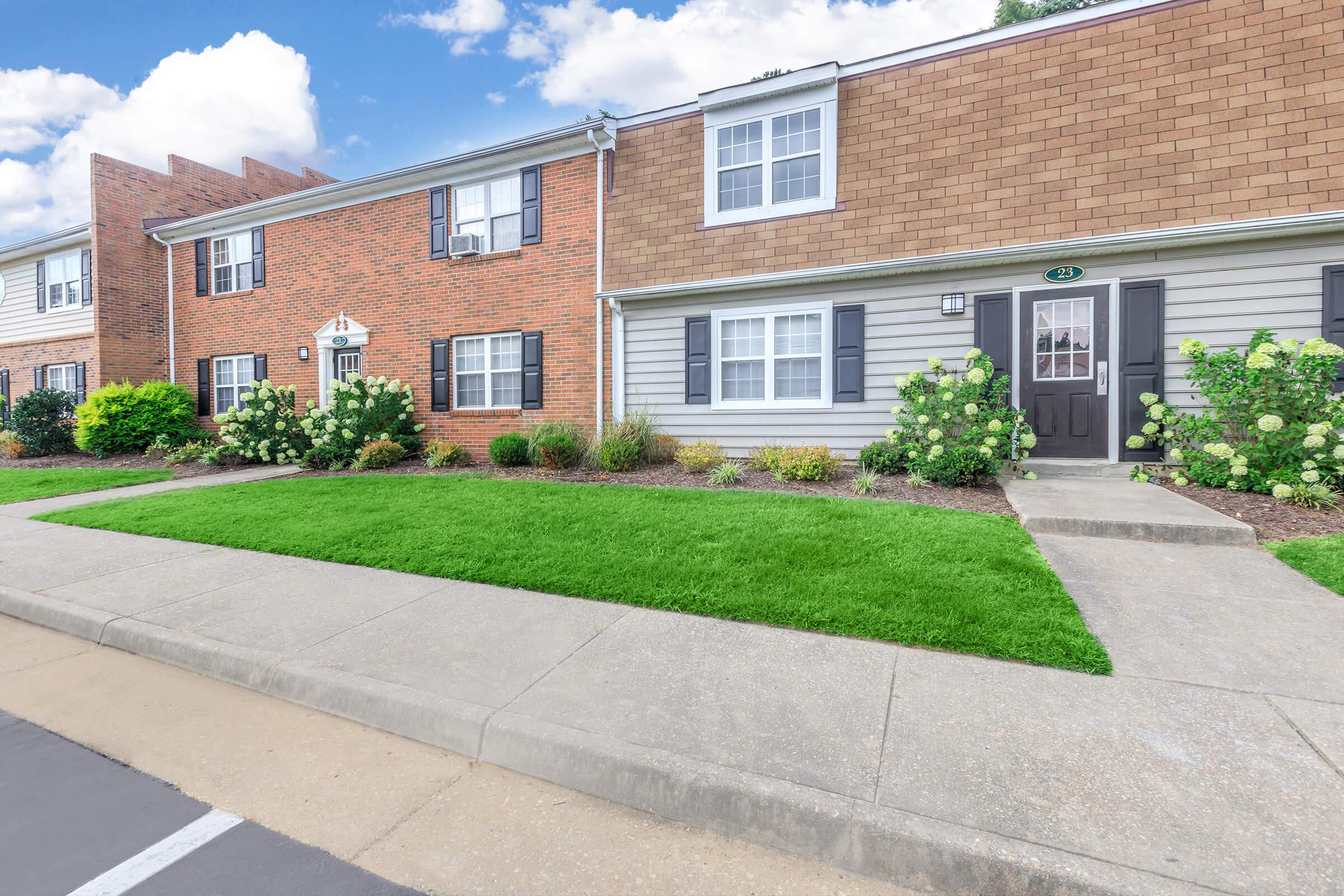 a large brick building with grass in front of a house