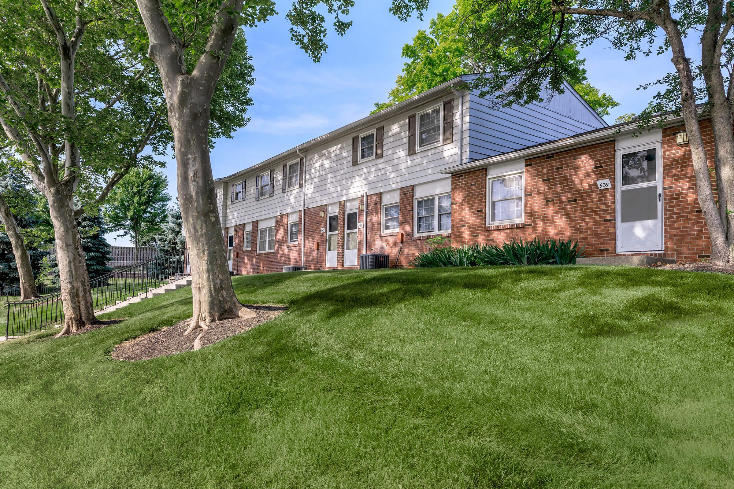 a large brick building with grass in front of a house