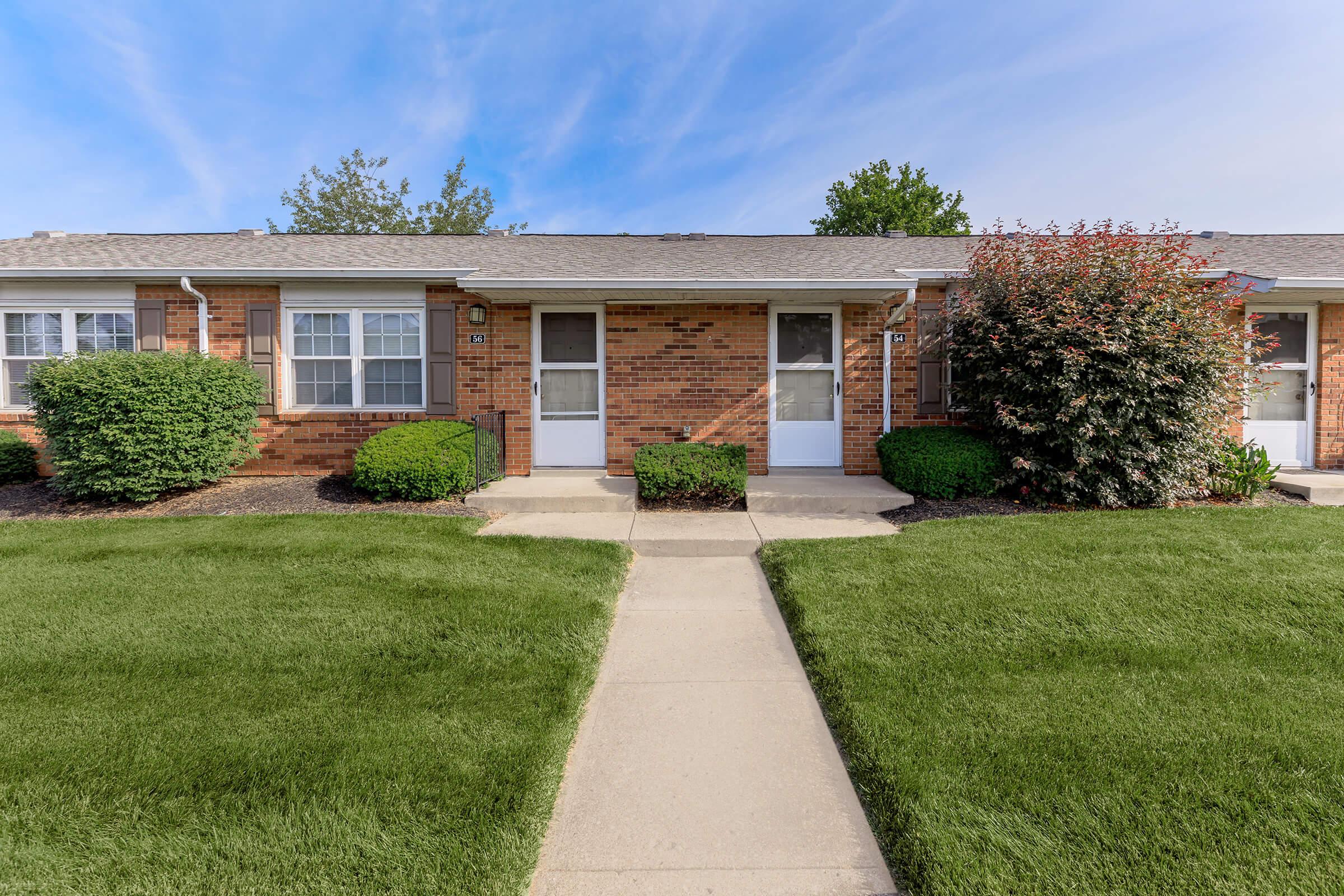 a large brick building with grass in front of a house