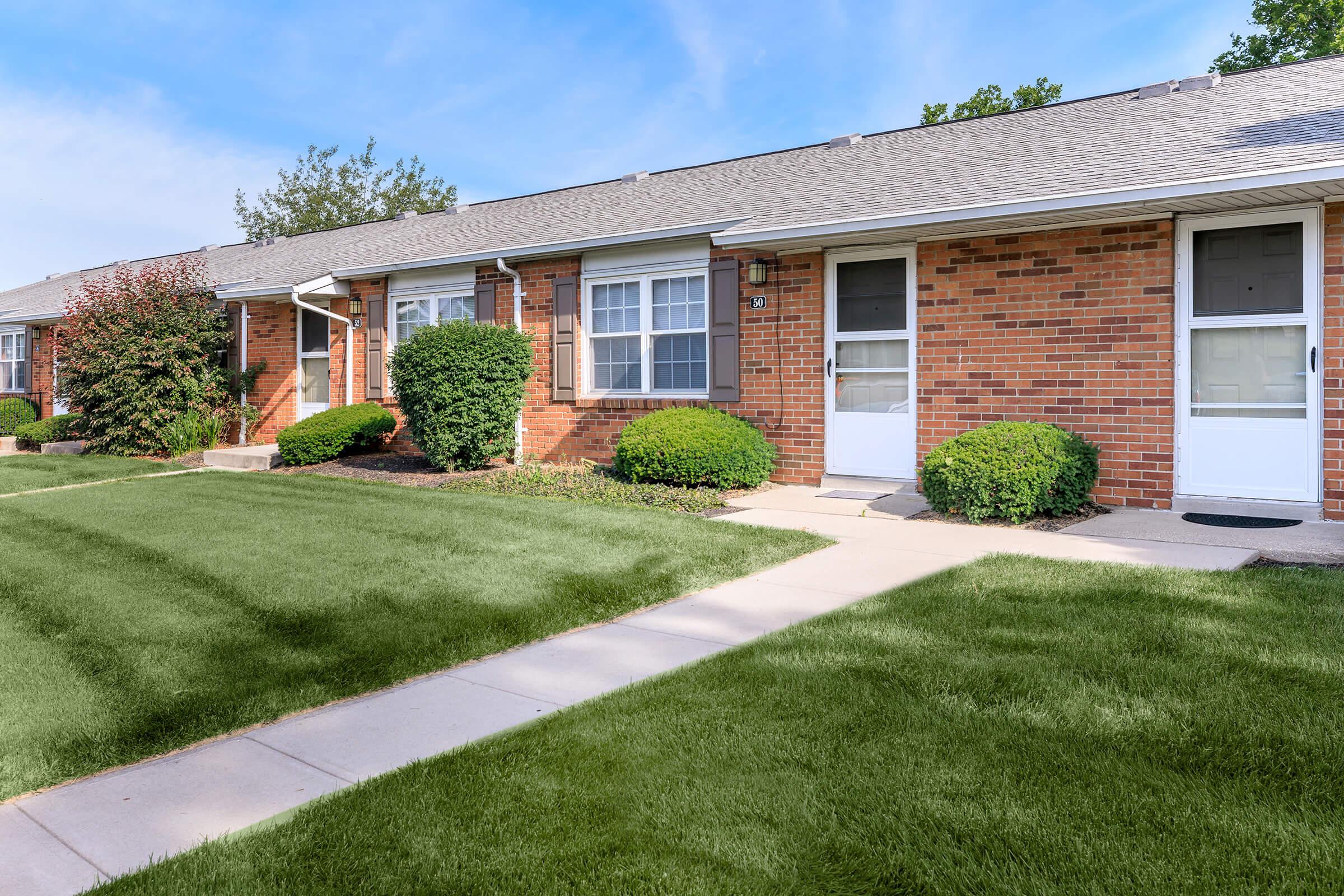 a house with a lawn in front of a brick building