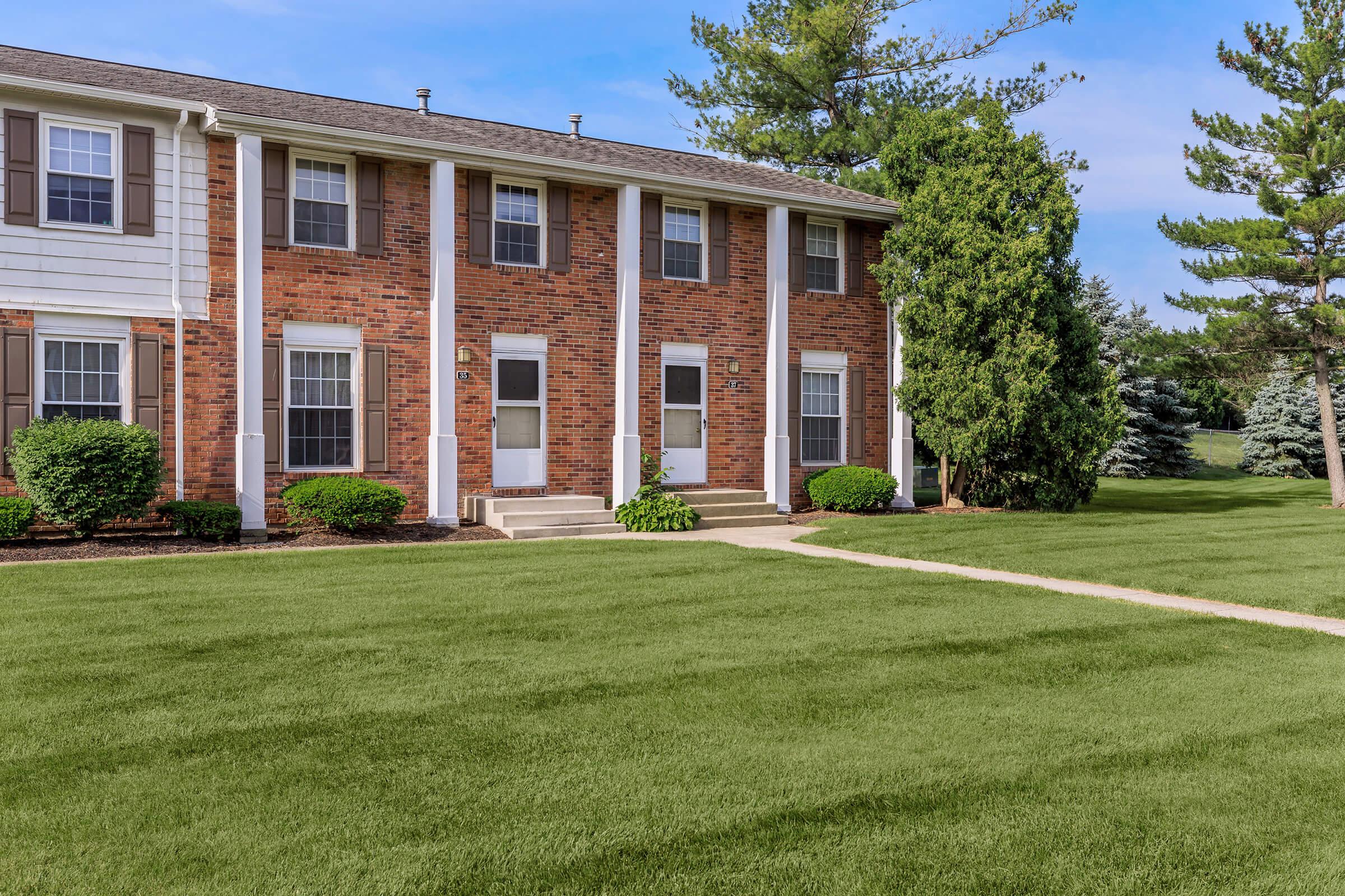 a house with a lawn in front of a brick building