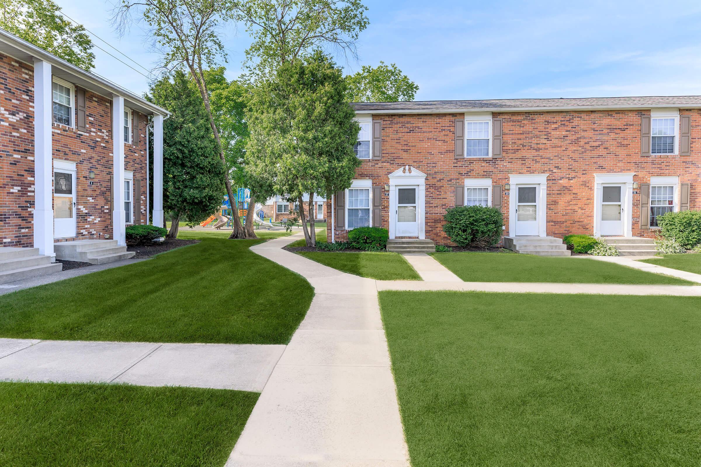 a house with a lawn in front of a brick building