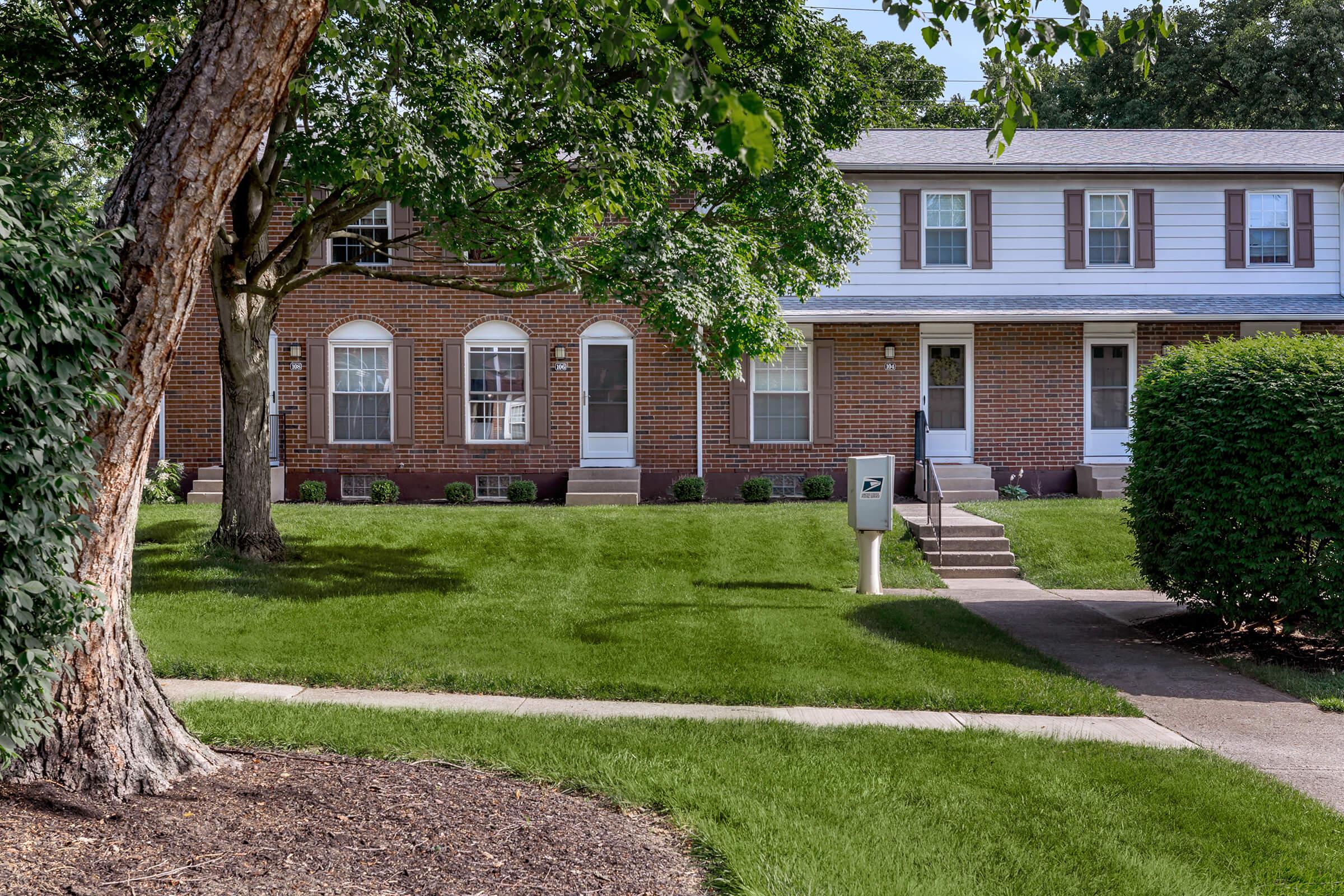 a house with a lawn in front of a brick building