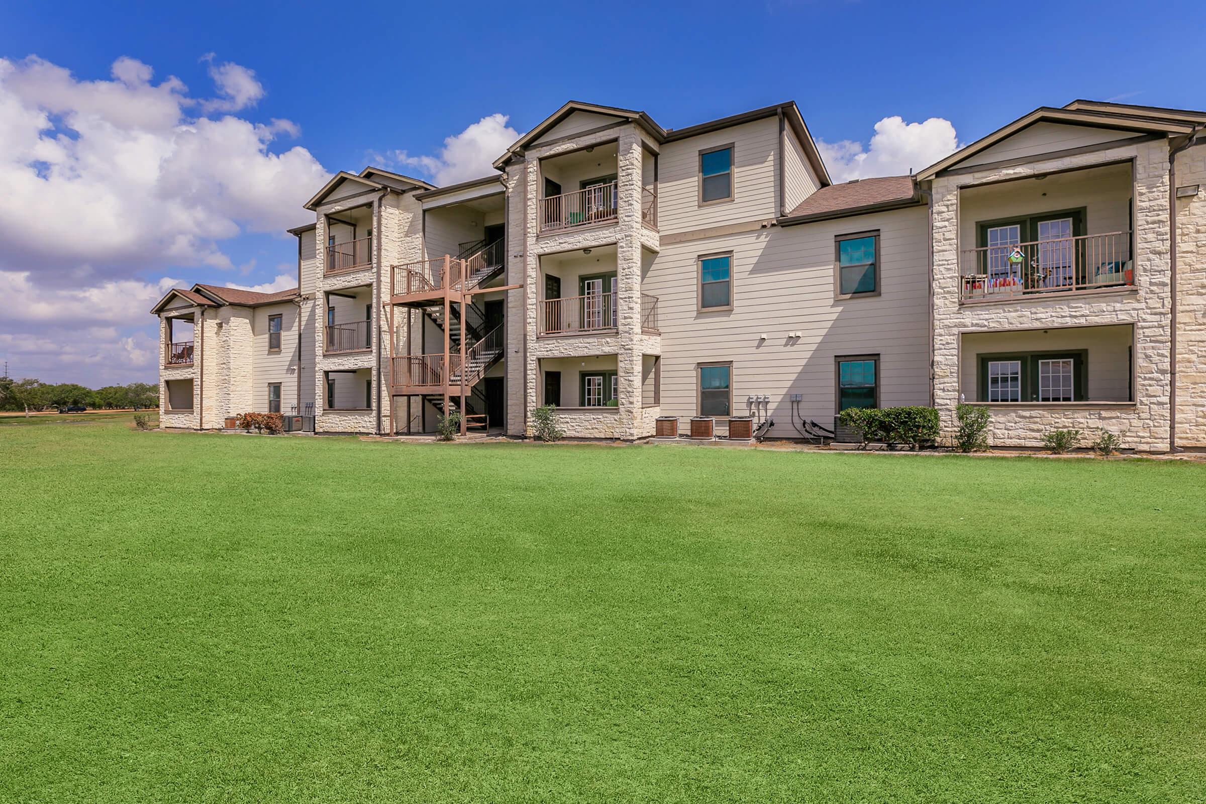 a large brick building with a grassy field