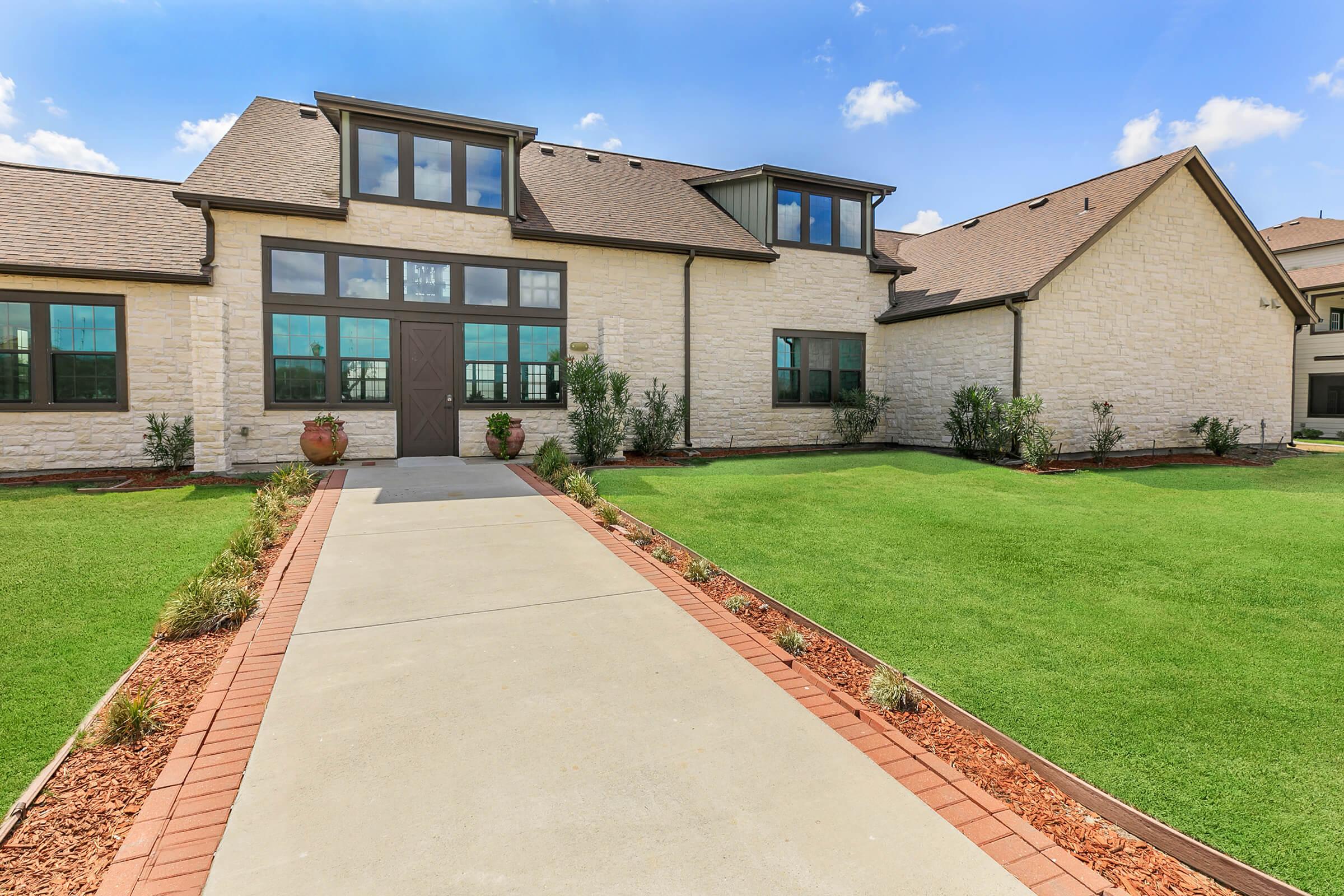 a large brick building with grass in front of a house