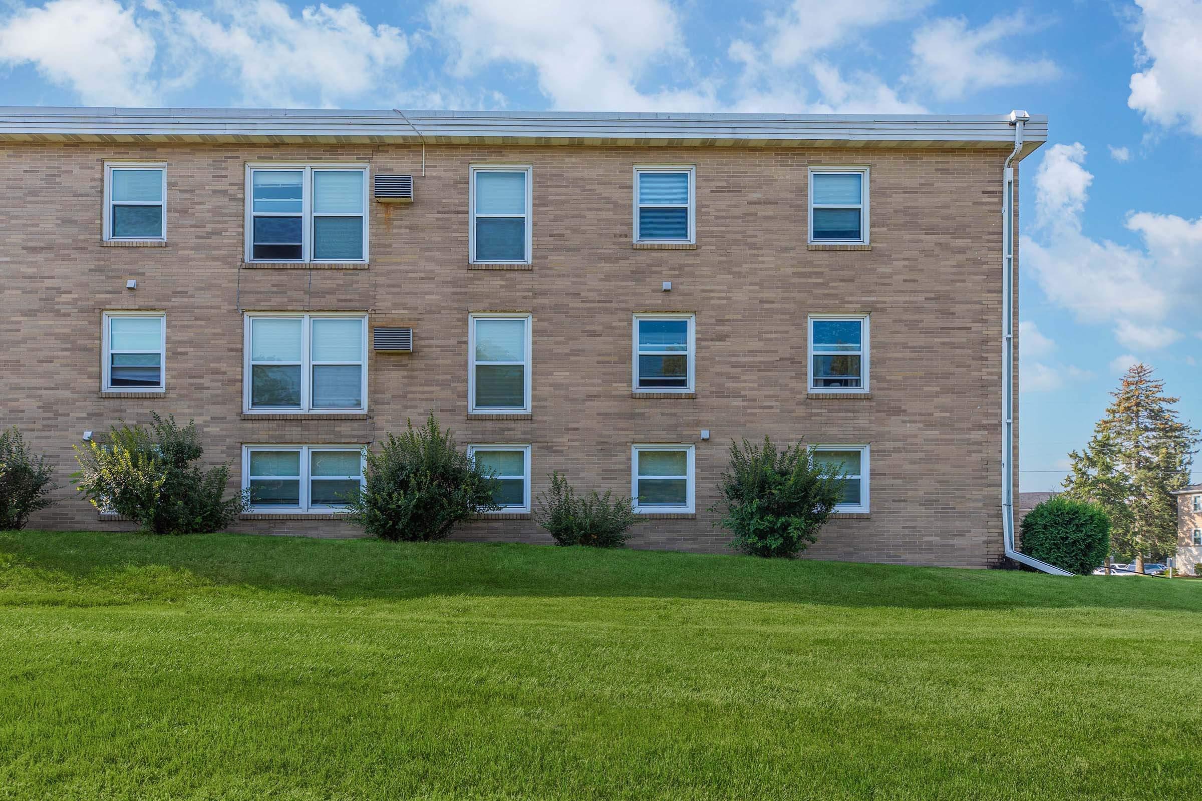 a large brick building with a grassy field